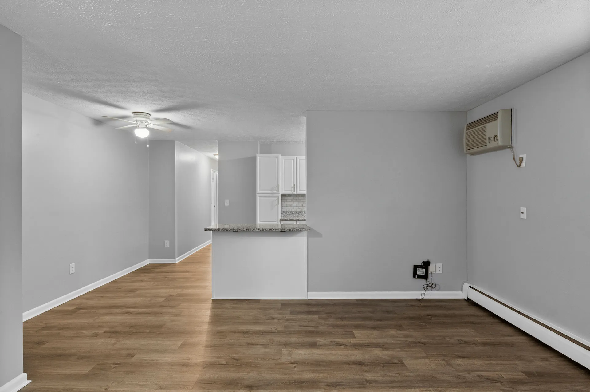 Inviting open-concept living area with hardwood flooring and natural light, featuring a view into the bright kitchen.