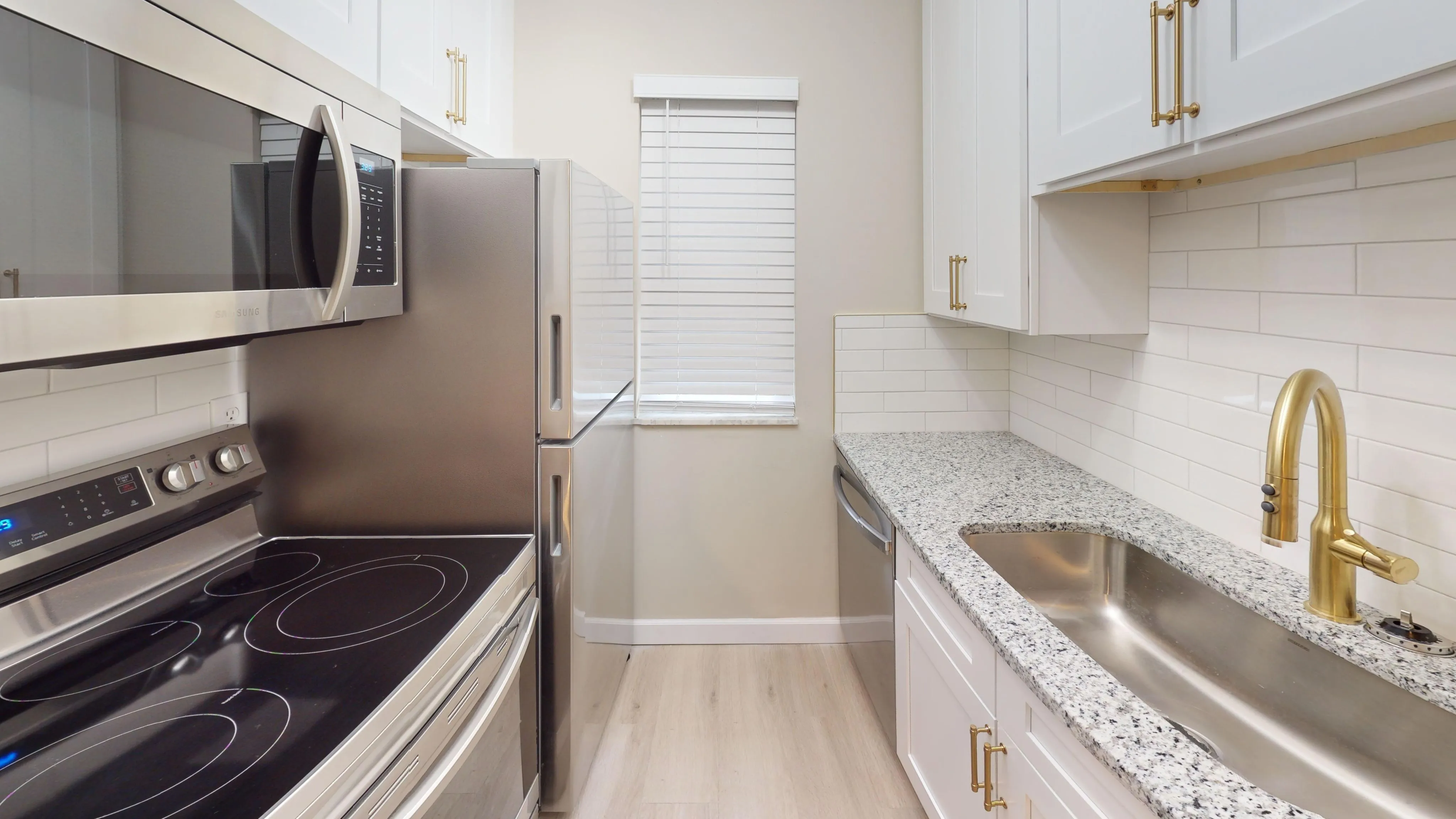 Modern kitchen featuring sleek stainless steel appliances, granite countertops, and white cabinetry.