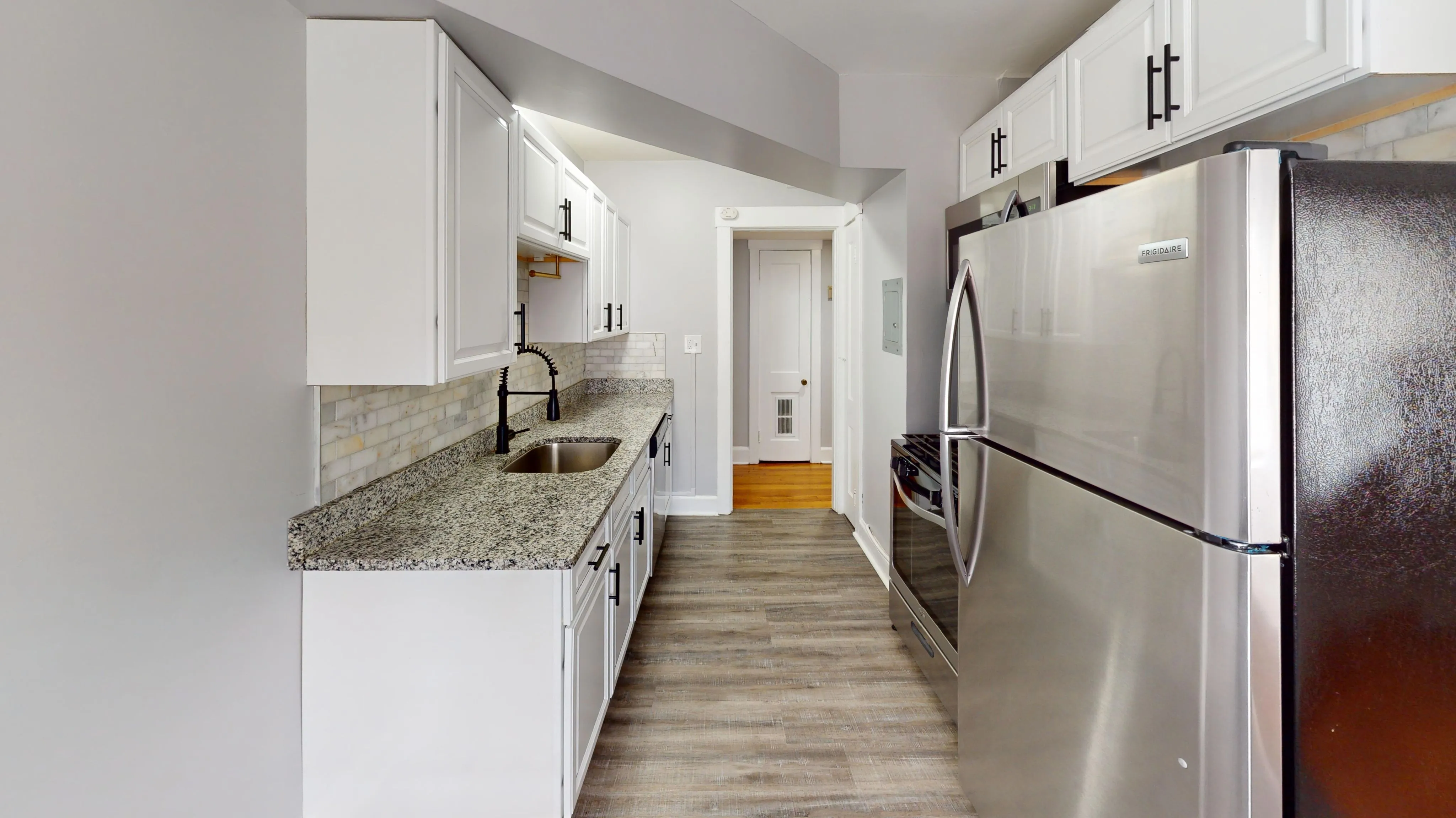 Contemporary kitchen with granite countertops, stainless steel appliances, and white cabinetry.