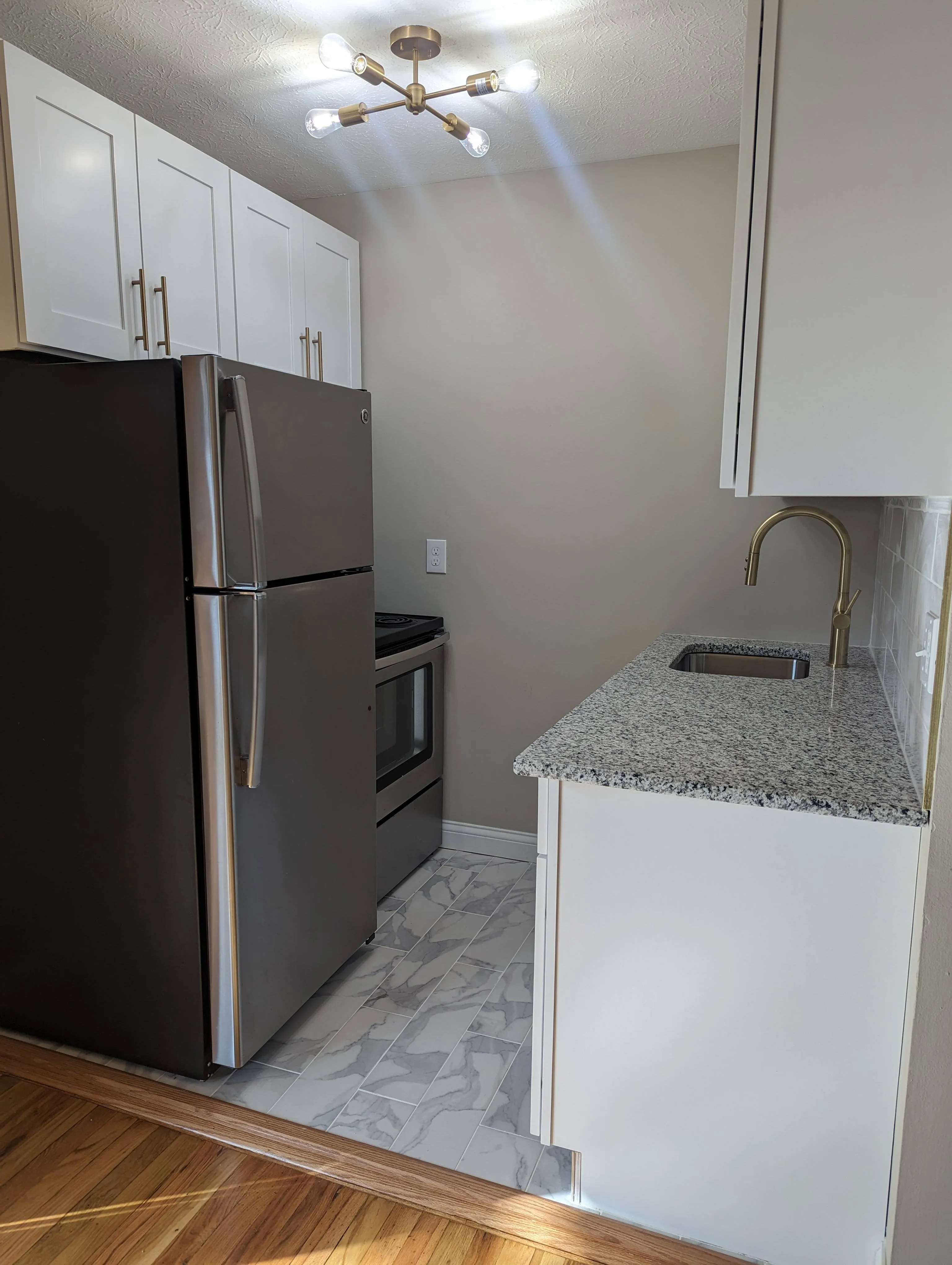 Modern kitchen with stainless steel appliances, granite countertops, and elegant lighting.