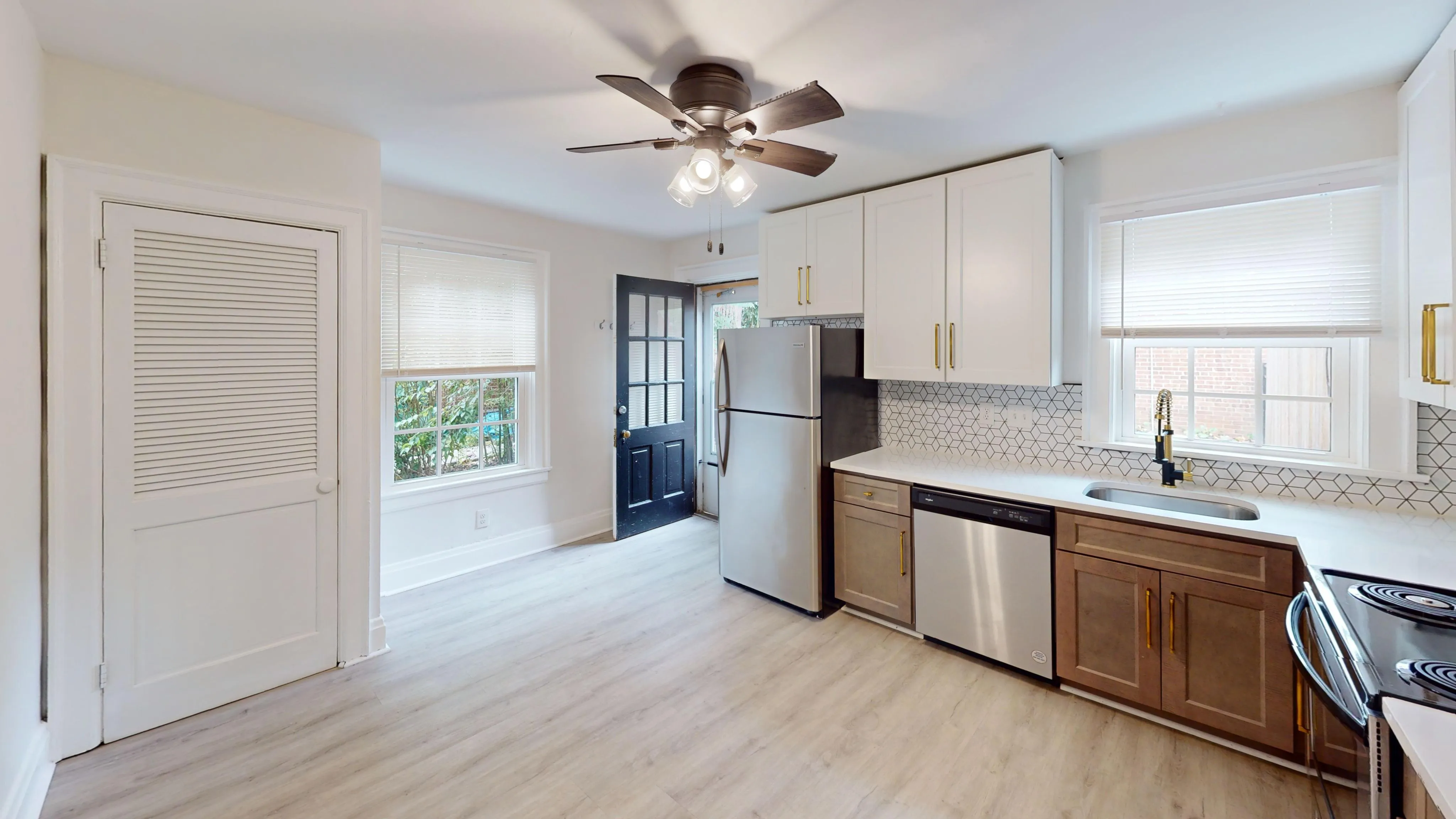 Bright and modern kitchen with sleek stainless steel appliances, white cabinetry, and a geometric backsplash design.