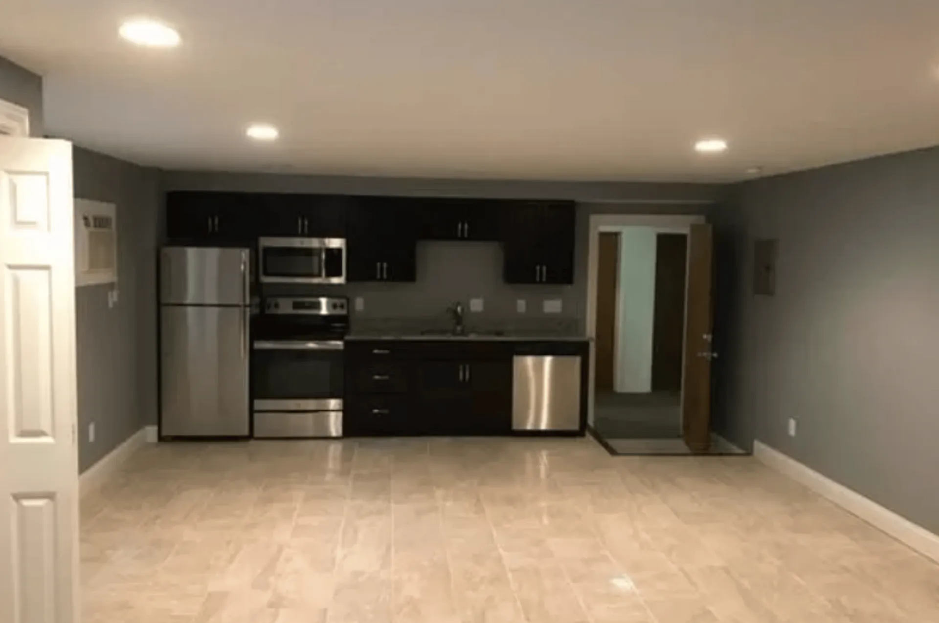 Modern kitchen with sleek stainless steel appliances, tiled flooring, and stylish dark cabinetry.