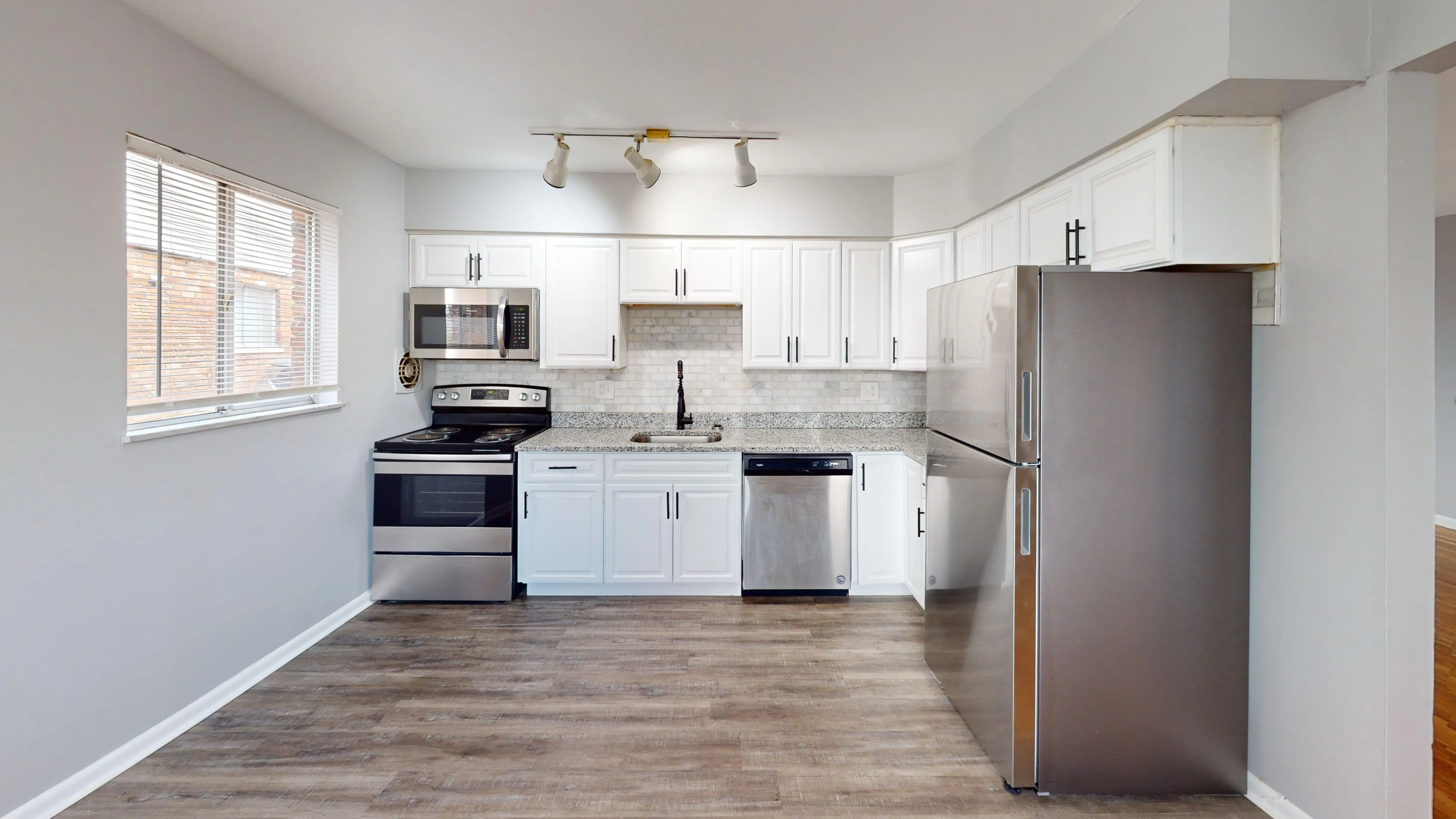 Modern kitchen with sleek stainless steel appliances, white cabinetry, and granite countertops offering a bright and inviting cooking space.