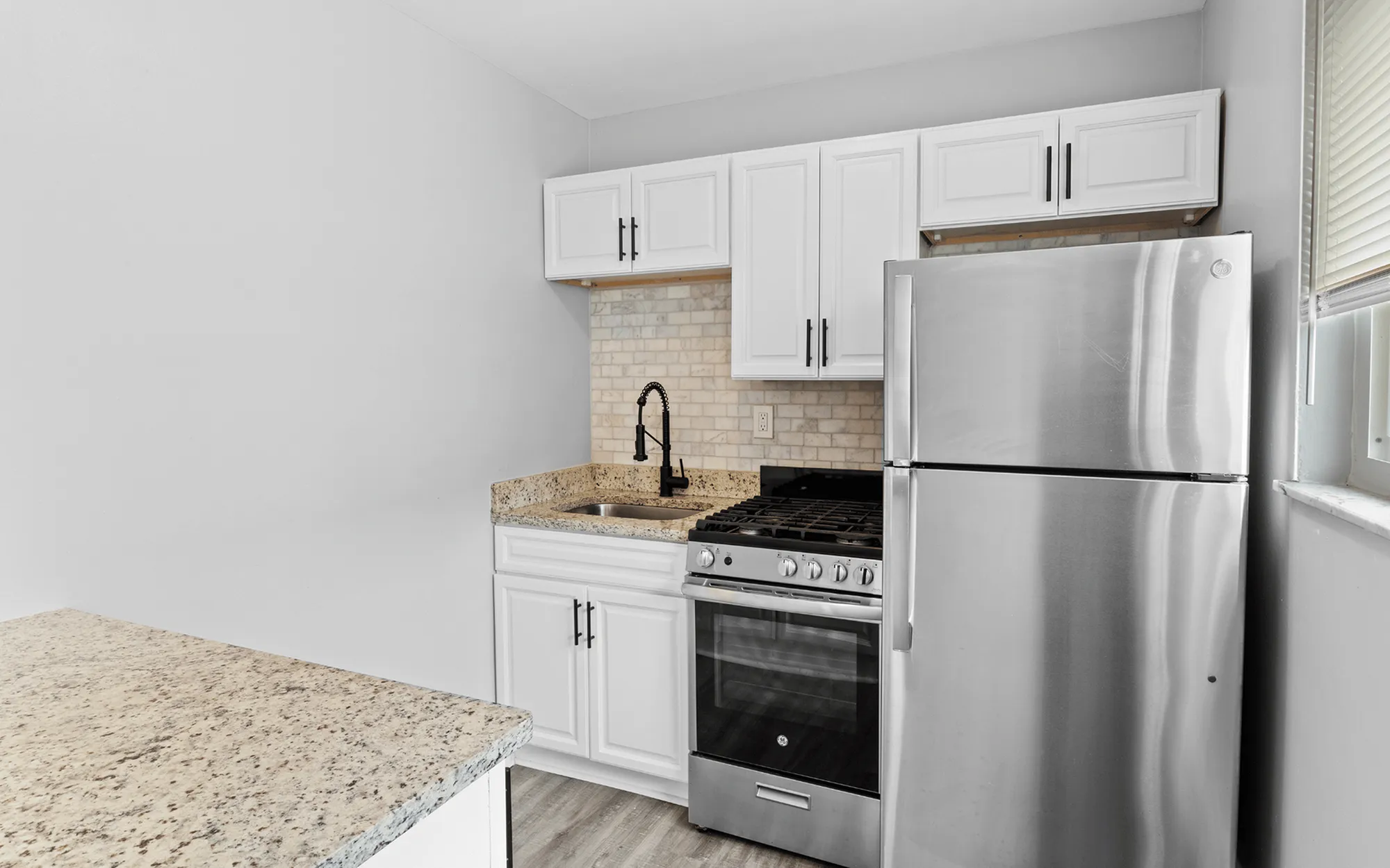 Modern kitchen with sleek stainless steel appliances, granite countertops, and elegant white cabinetry.