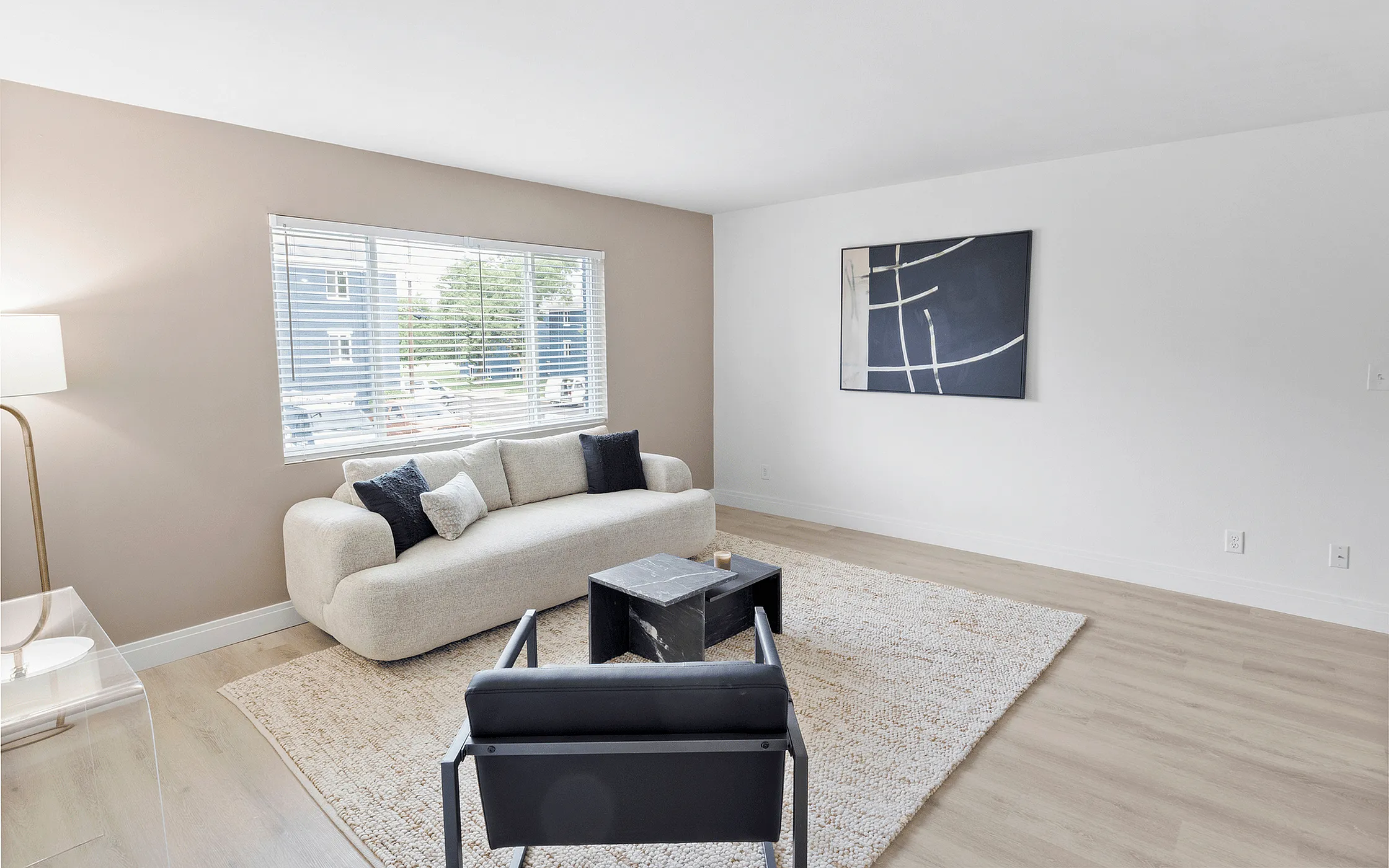 Bright and inviting living room with modern decor, featuring a cozy beige sofa and large window for natural light.