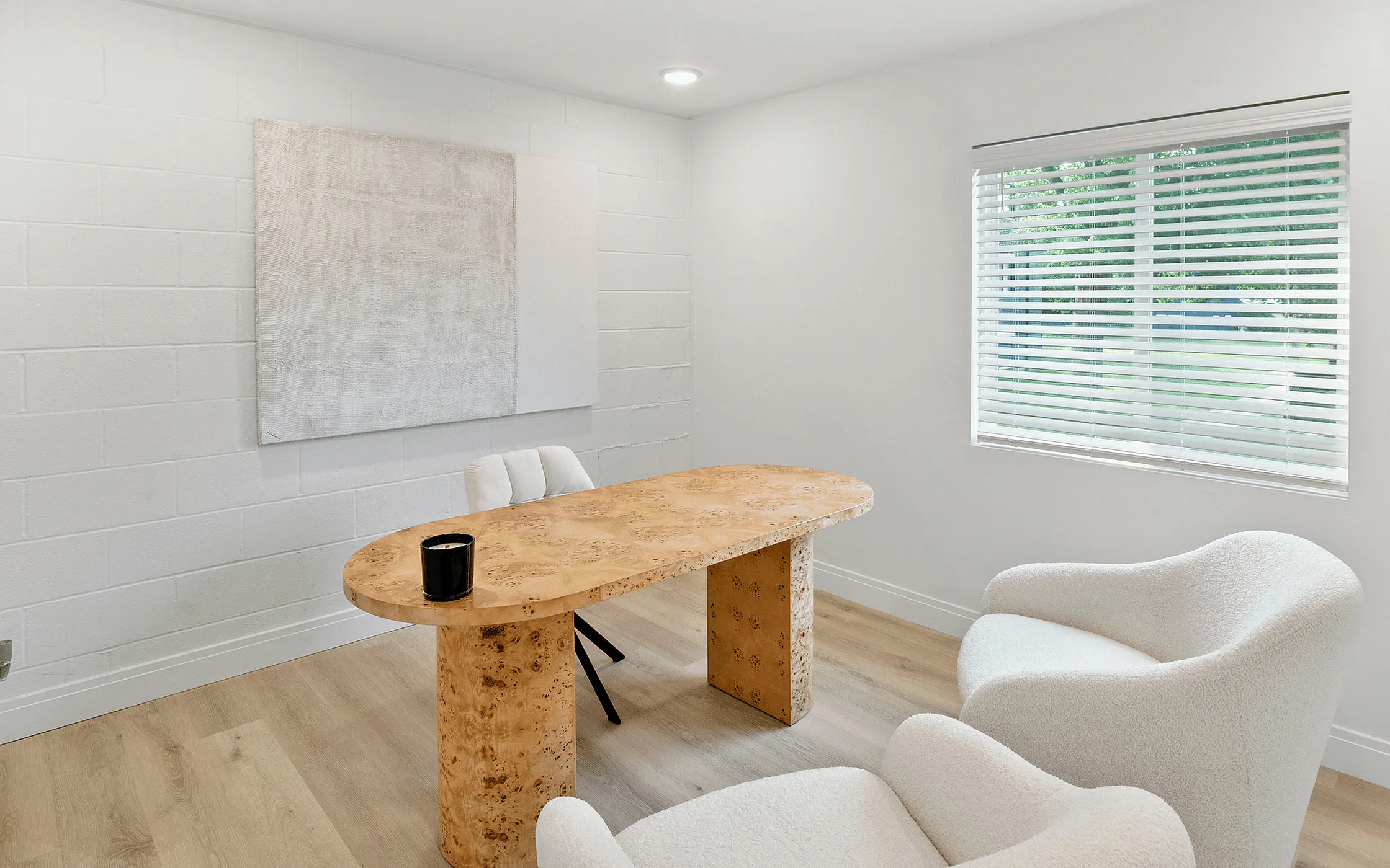 Elegant home office with a unique wooden table, plush white chairs, and a large window letting in natural light.