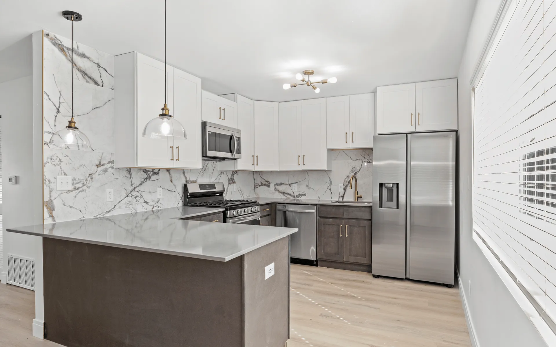 Contemporary kitchen with elegant marble backsplash, sleek white cabinetry, and modern stainless steel appliances.