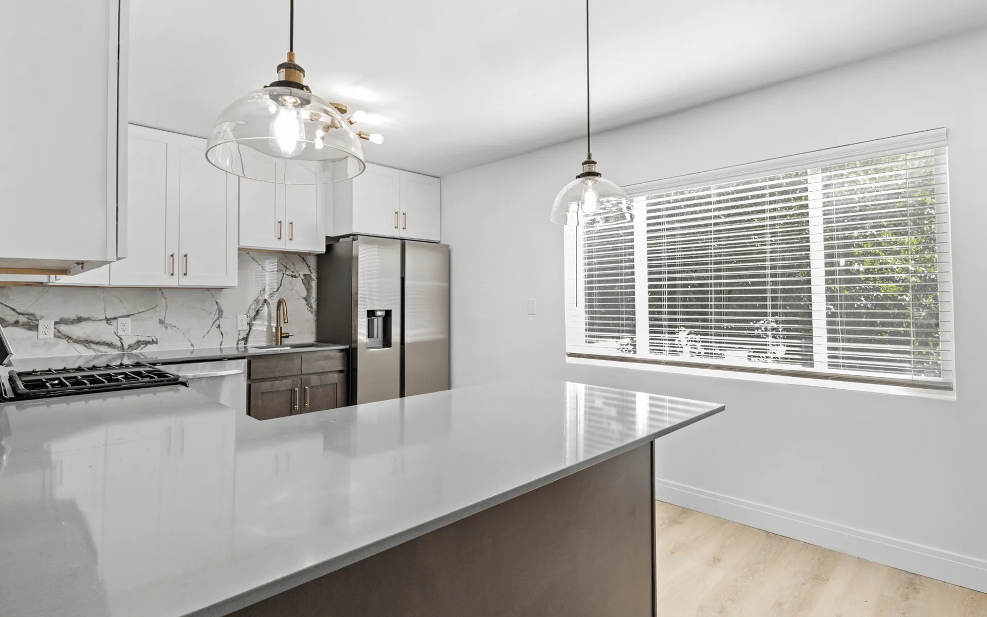 Sleek modern kitchen with stainless steel appliances, elegant marble backsplash, and abundant natural light.