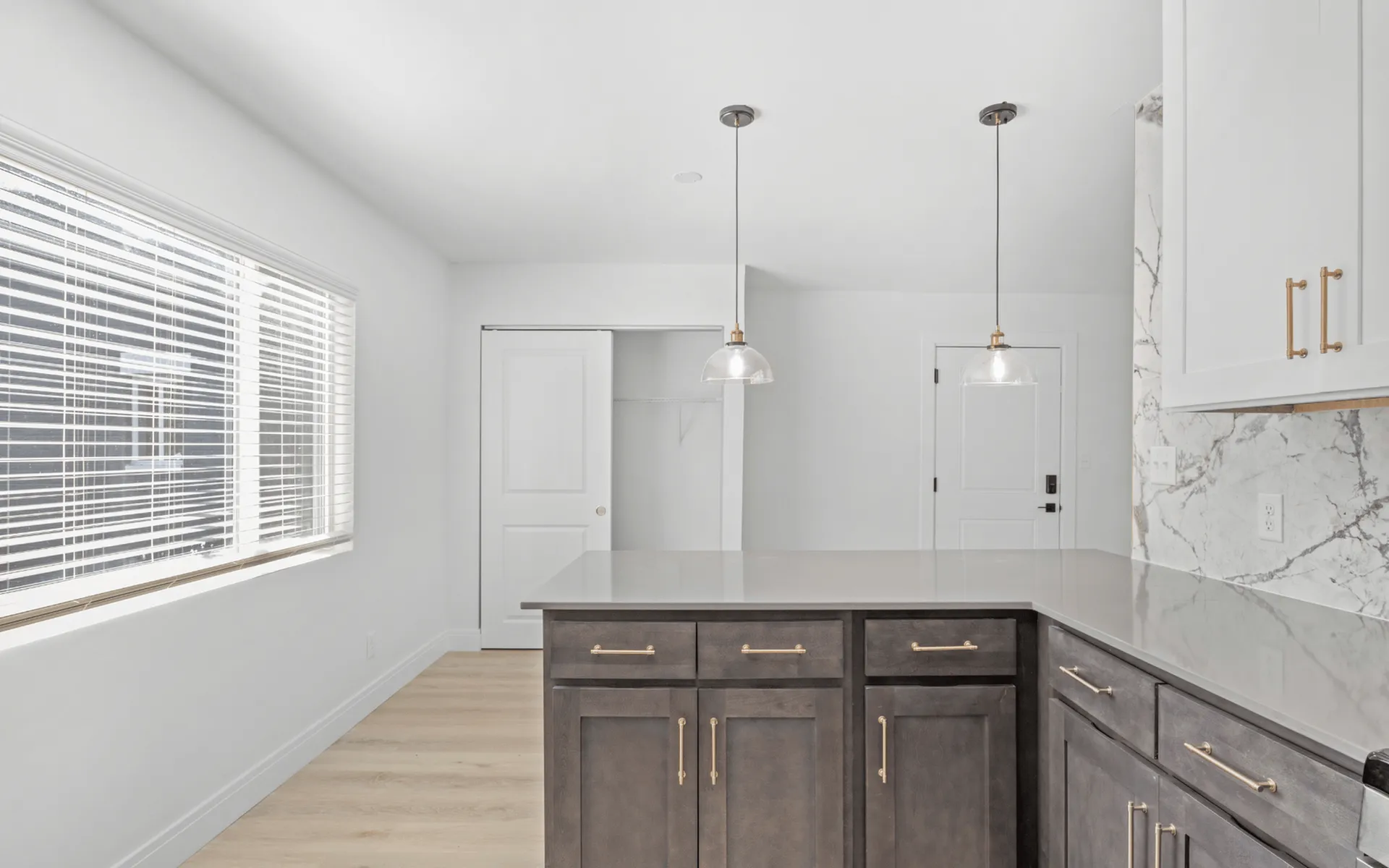 Modern kitchen with elegant pendant lighting, marble backsplash, and large island counter.