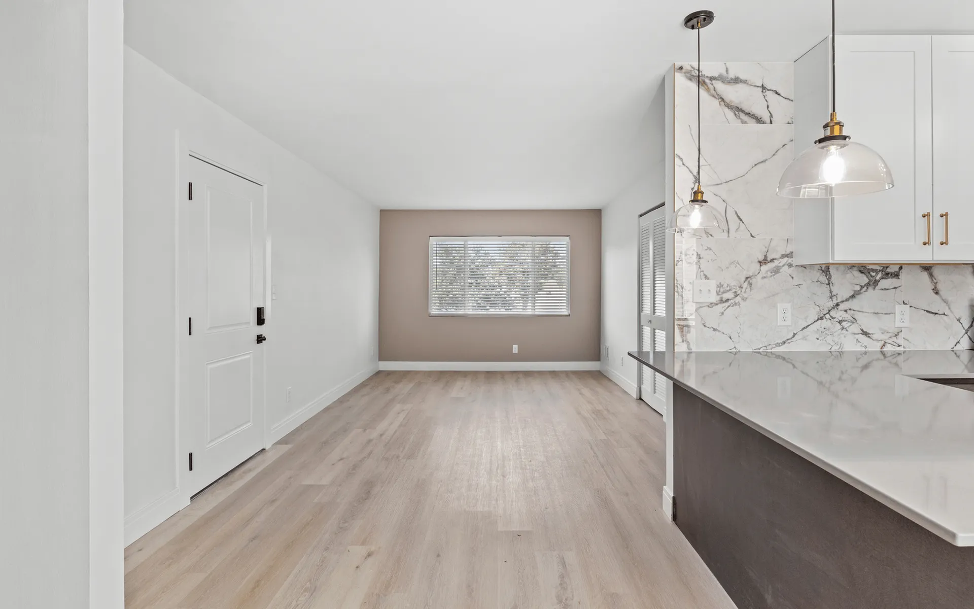 Bright, modern apartment featuring an open-concept living area with sleek quartz countertops, elegant marble accents, and hardwood flooring.
