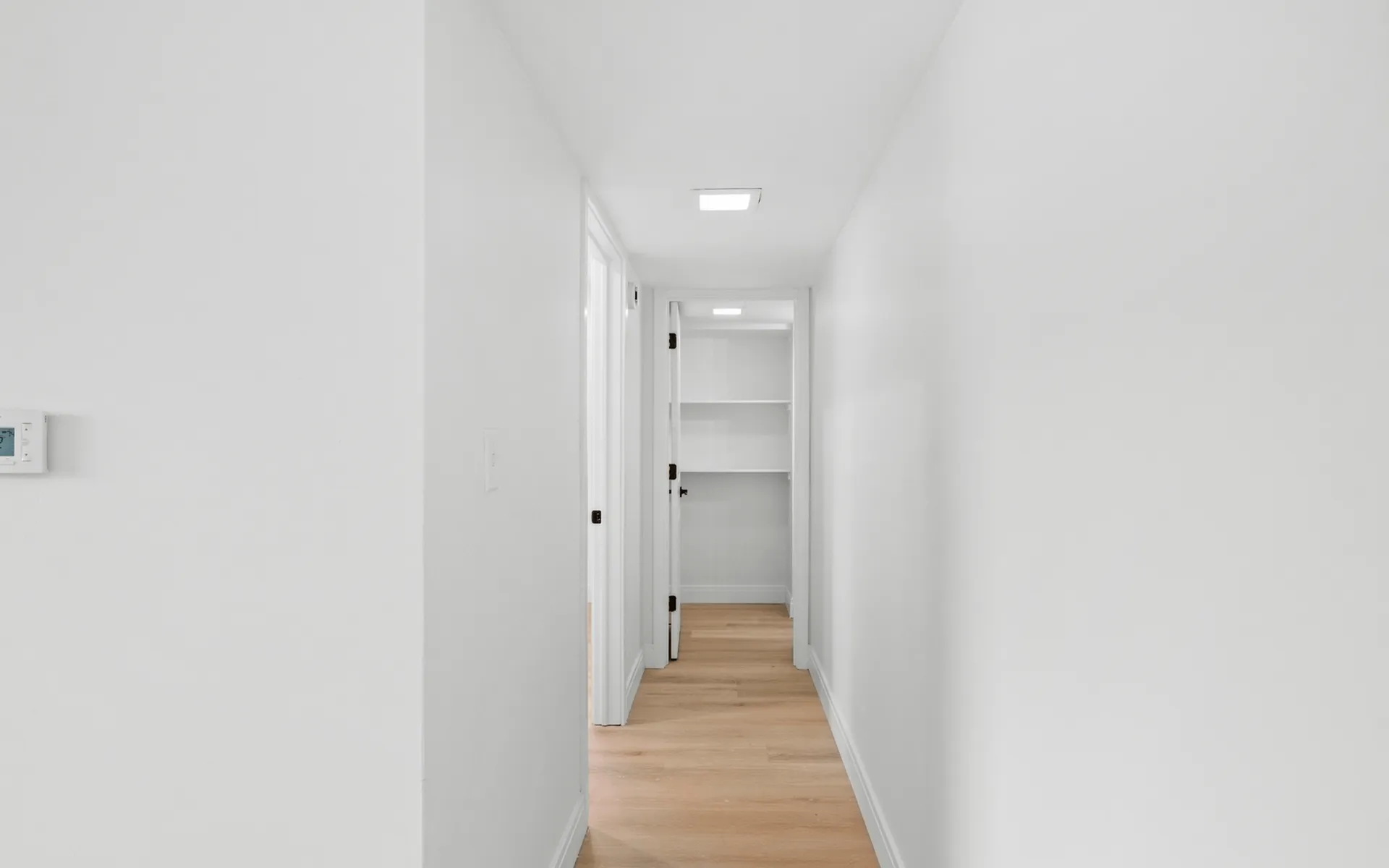 Bright, minimalist hallway with light wood flooring and built-in shelving, perfect for an elegant home environment.