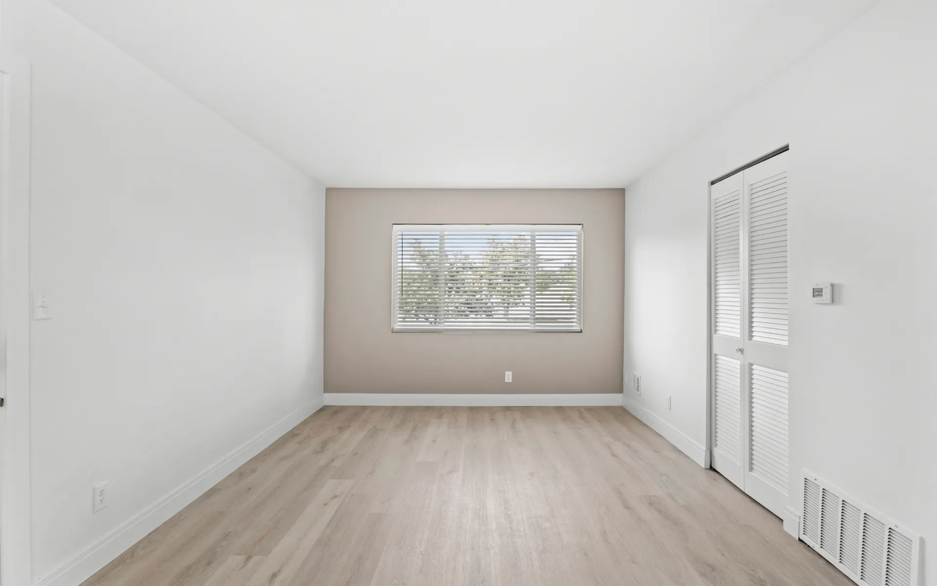 Bright, welcoming room with elegant wood flooring and ample natural light through wide windows.