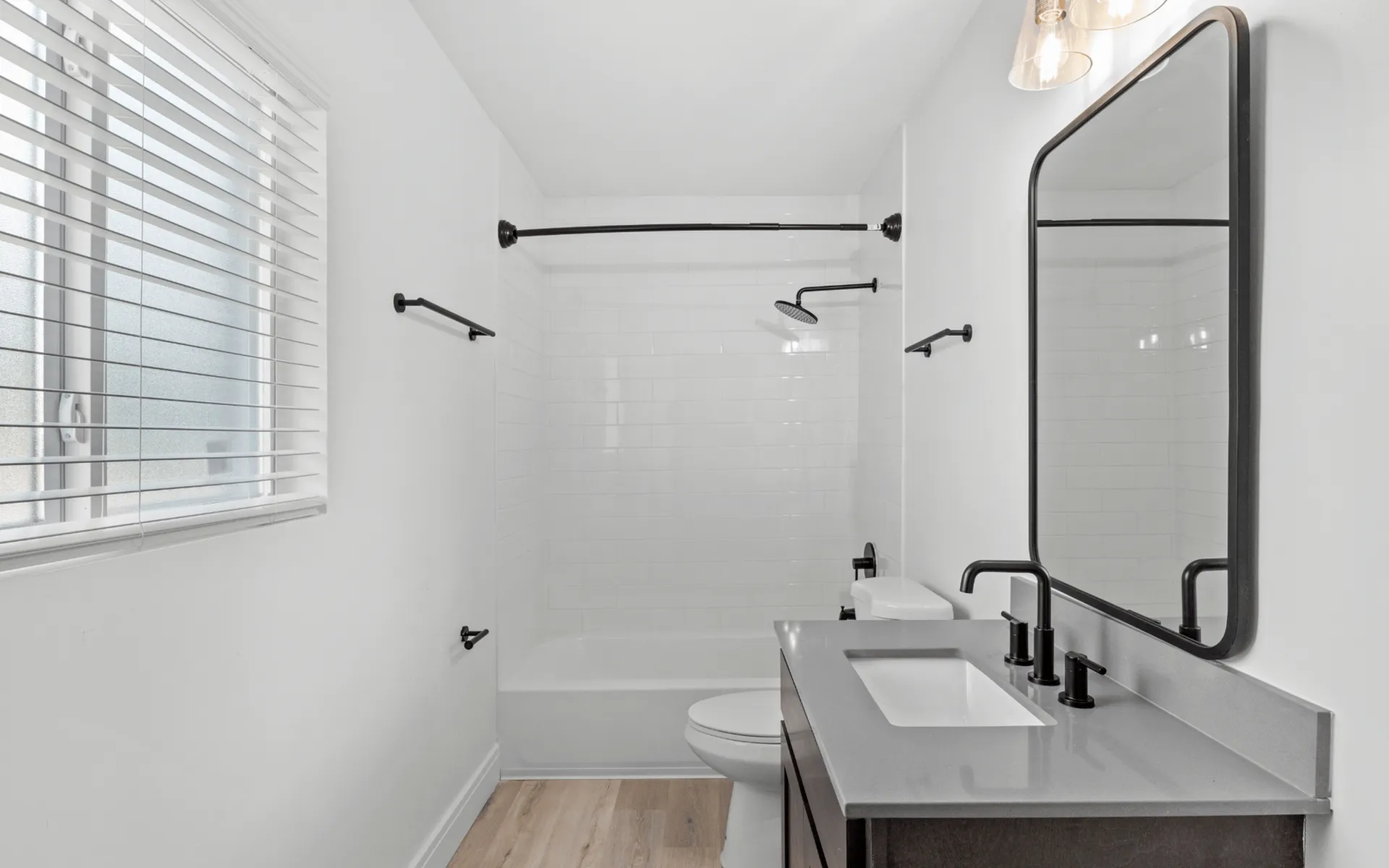 Modern bathroom featuring sleek black fixtures, a large mirror, and a bright ambiance with natural light.