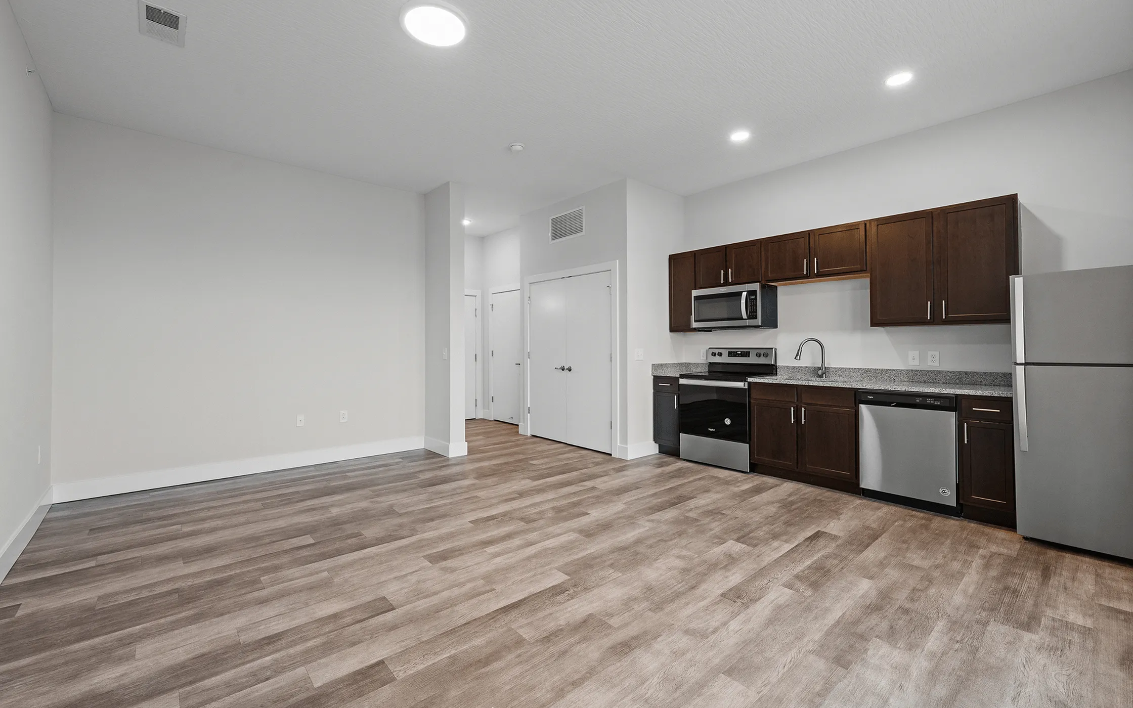 Modern open-concept kitchen with sleek dark cabinetry, stainless steel appliances, and elegant wood flooring.