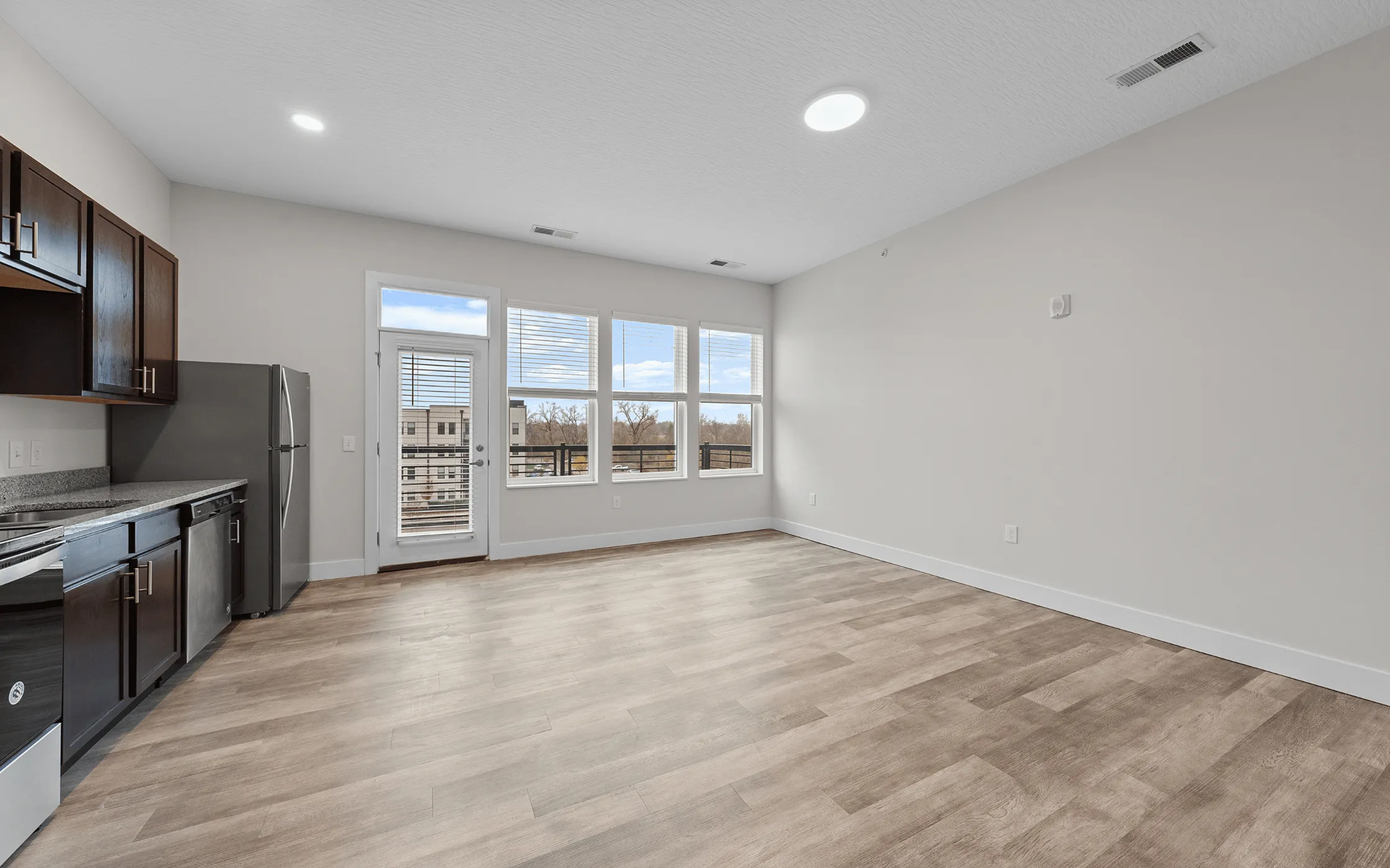 Modern open-concept kitchen and living area with sleek appliances, large windows, and elegant flooring.