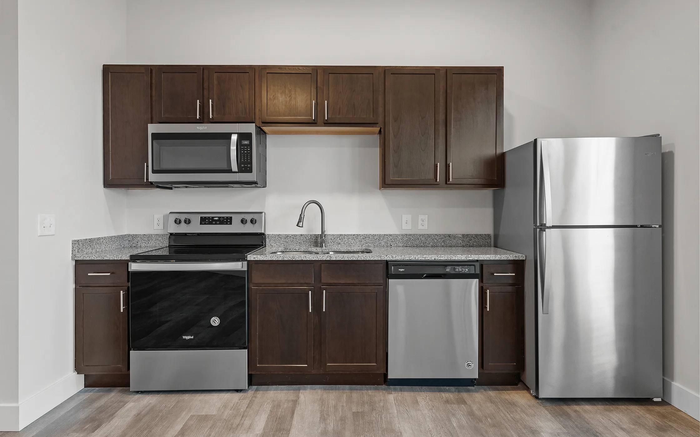 Modern kitchen with sleek stainless steel appliances, elegant granite countertops, and rich wooden cabinets offering stylish functionality.