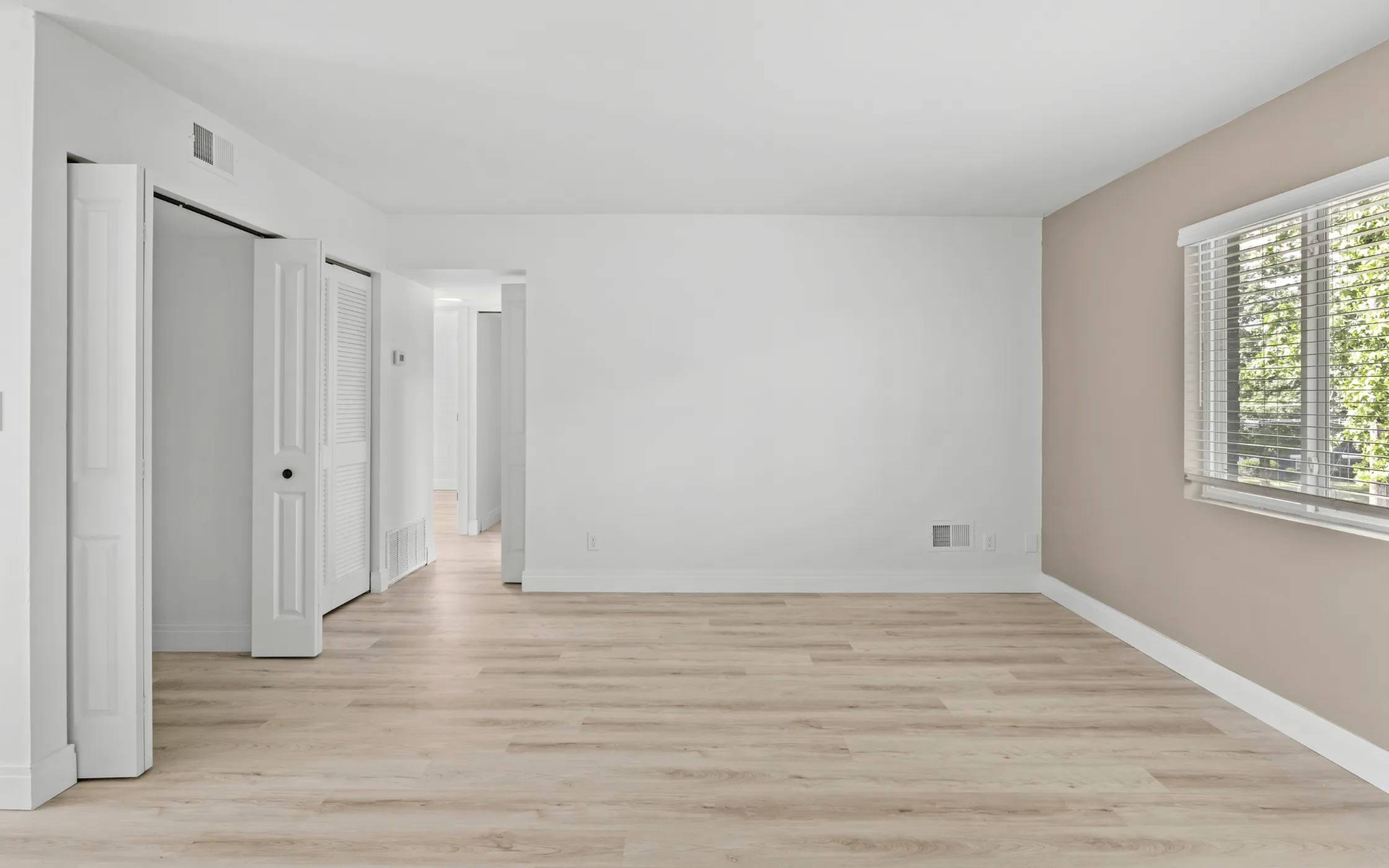 Bright and inviting room with light wood flooring, large window, and ample natural light, perfect for a modern living area.