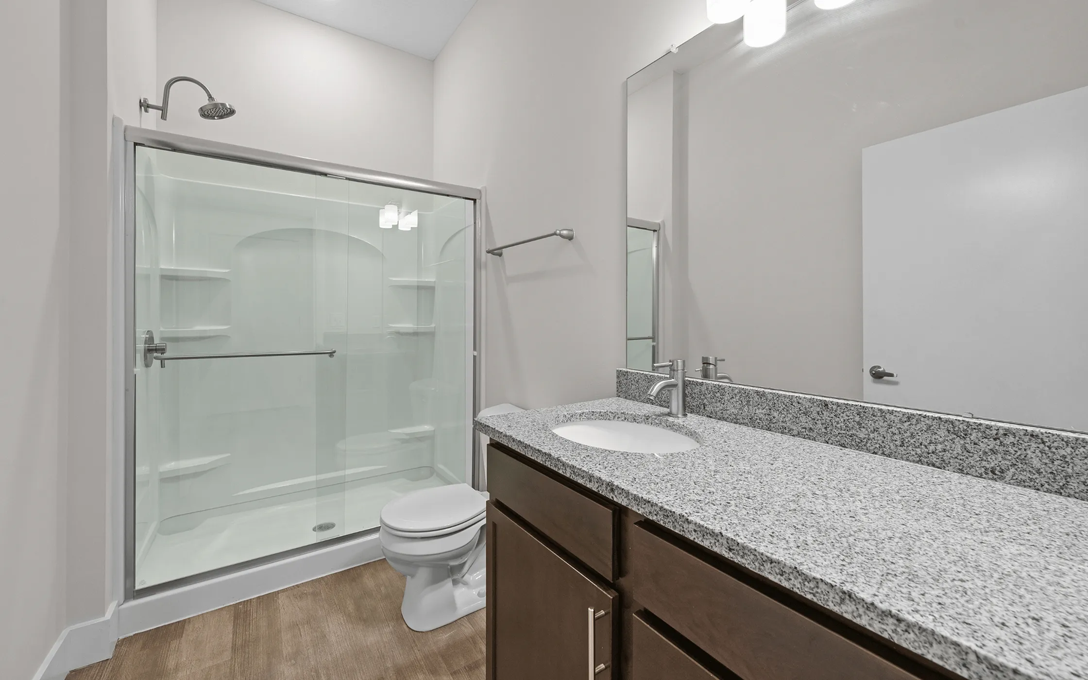 Modern bathroom with sleek granite countertop, elegant fixtures, and a spacious glass-enclosed shower.