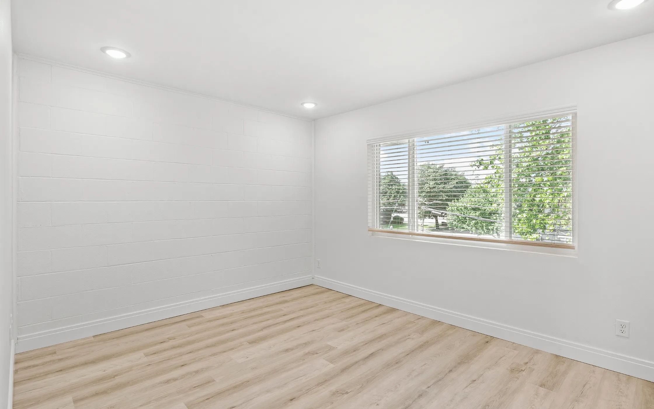 Bright and airy room with elegant hardwood floors, large window providing natural light and scenic views.