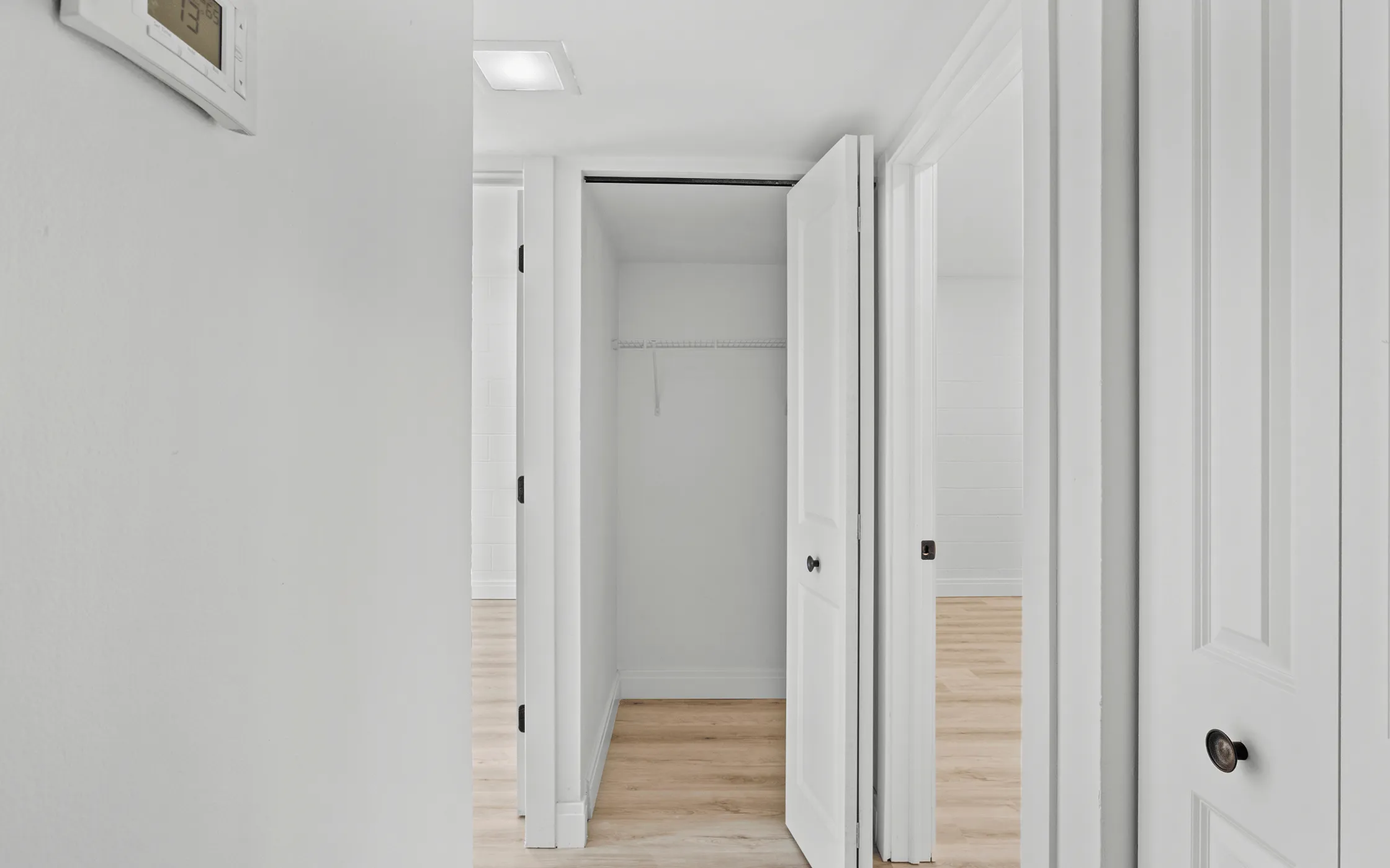 Bright and airy hallway with minimalist design, showcasing multiple white doors and sleek hardwood flooring.