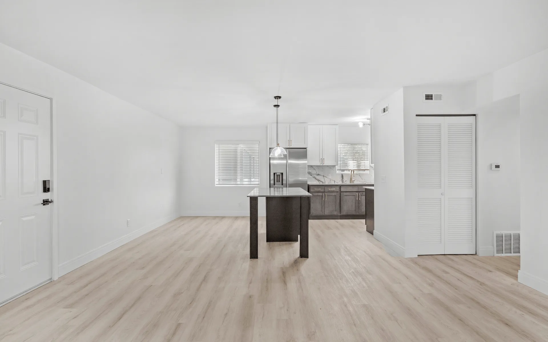 Bright and spacious open-concept living area with modern kitchen, featuring sleek cabinetry, a central island, and stylish lighting fixtures.