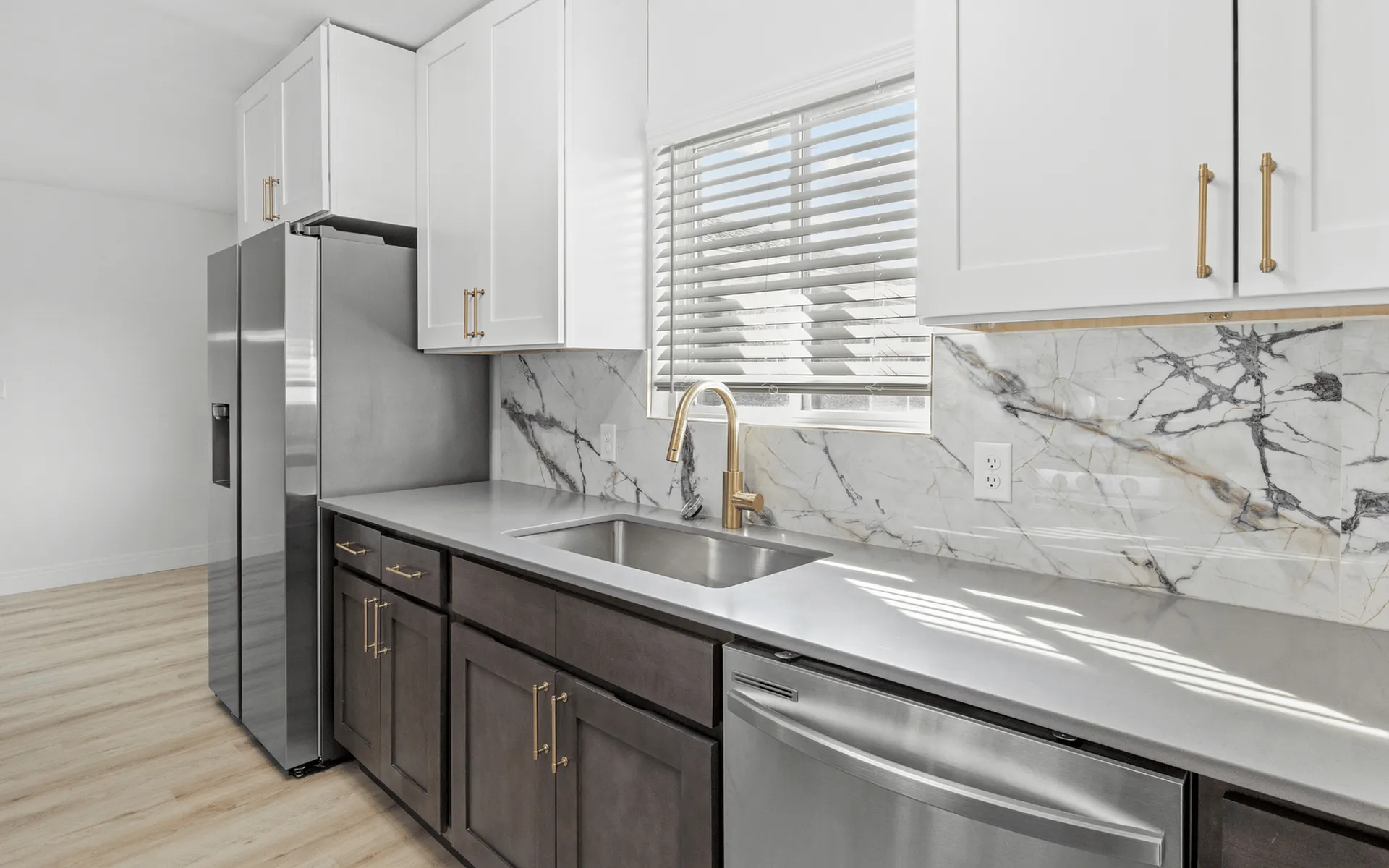 Modern kitchen with sleek stainless steel appliances, elegant marble backsplash, and stylish gold fixtures.