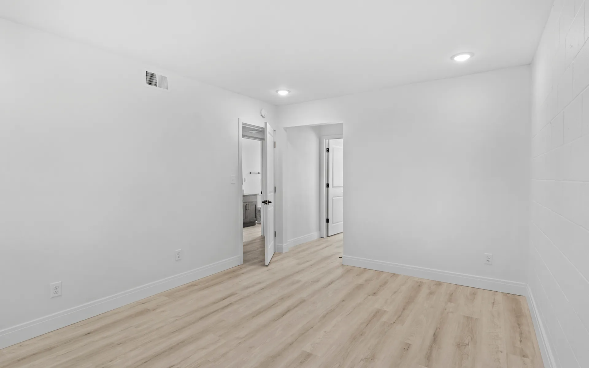 Bright and airy room with modern wood flooring, highlighting minimalist design and ample lighting.