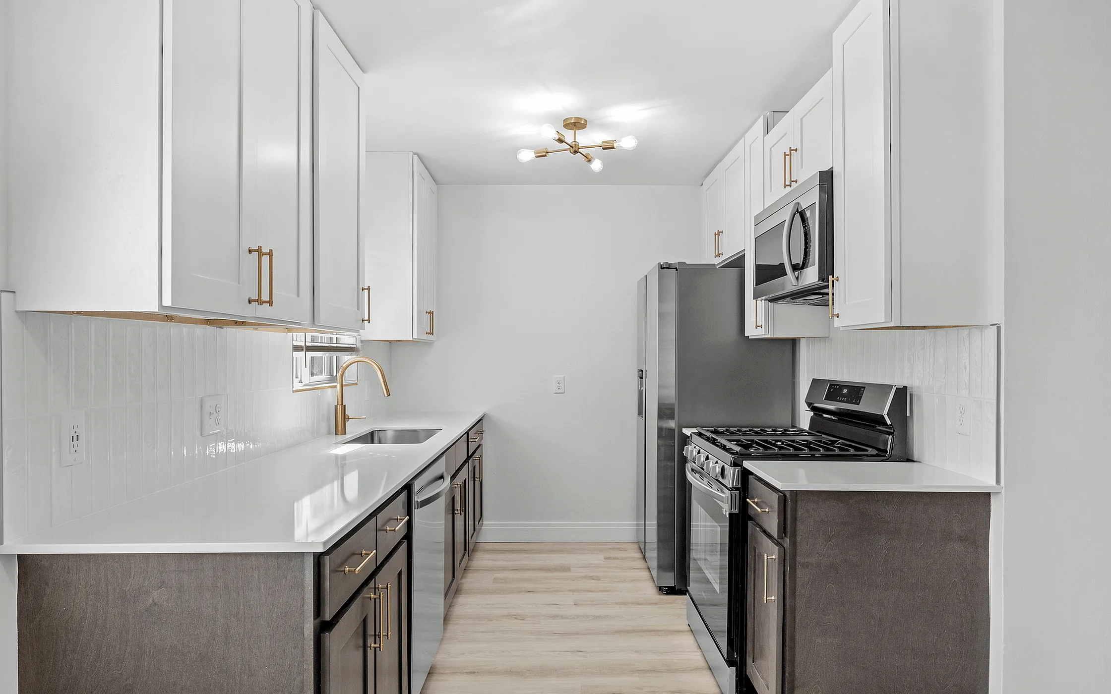 Modern kitchen with sleek white cabinets, elegant gold fixtures, and stainless steel appliances.
