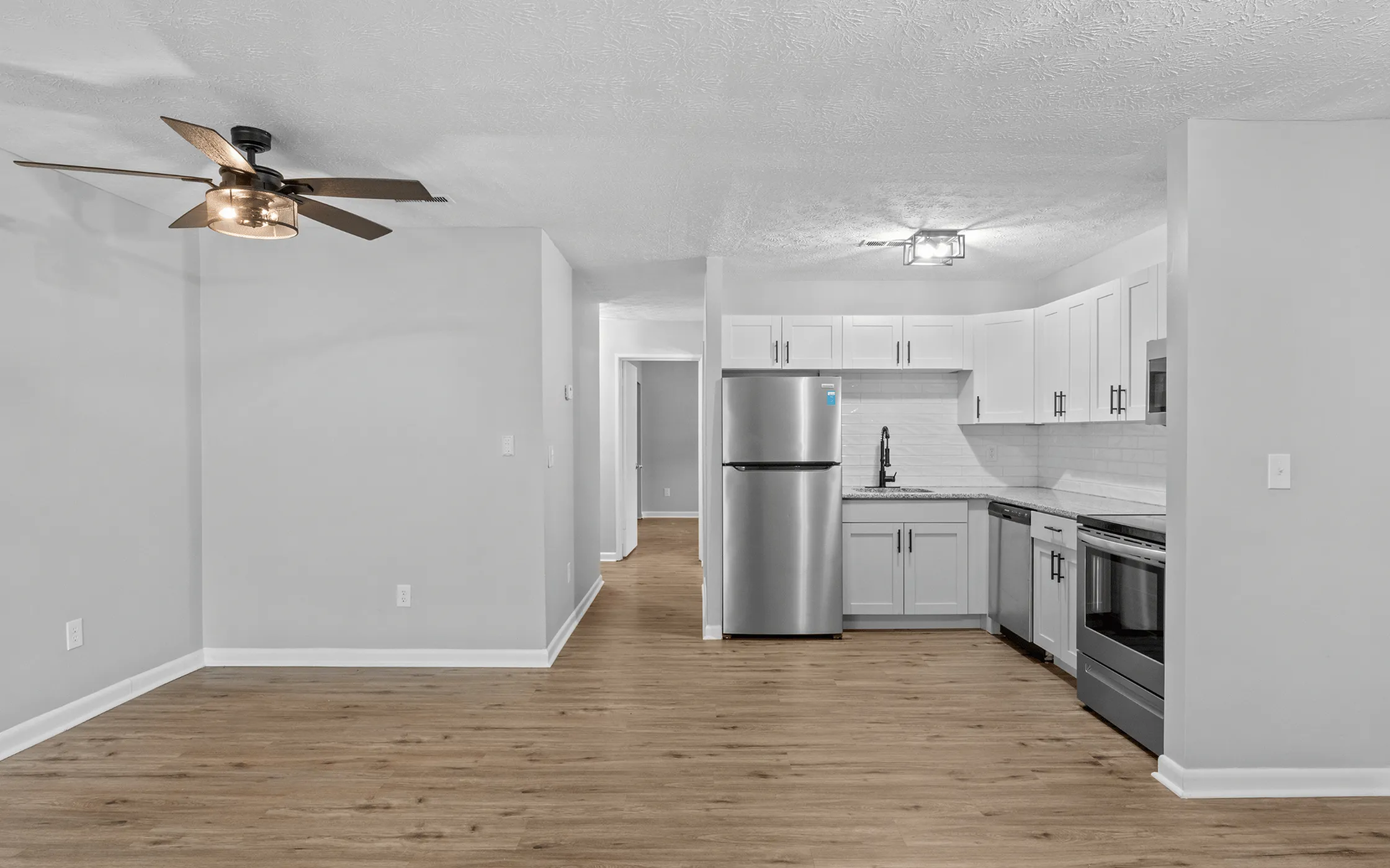 Modern open-concept kitchen with sleek stainless steel appliances, elegant white cabinetry, and stylish wood flooring.