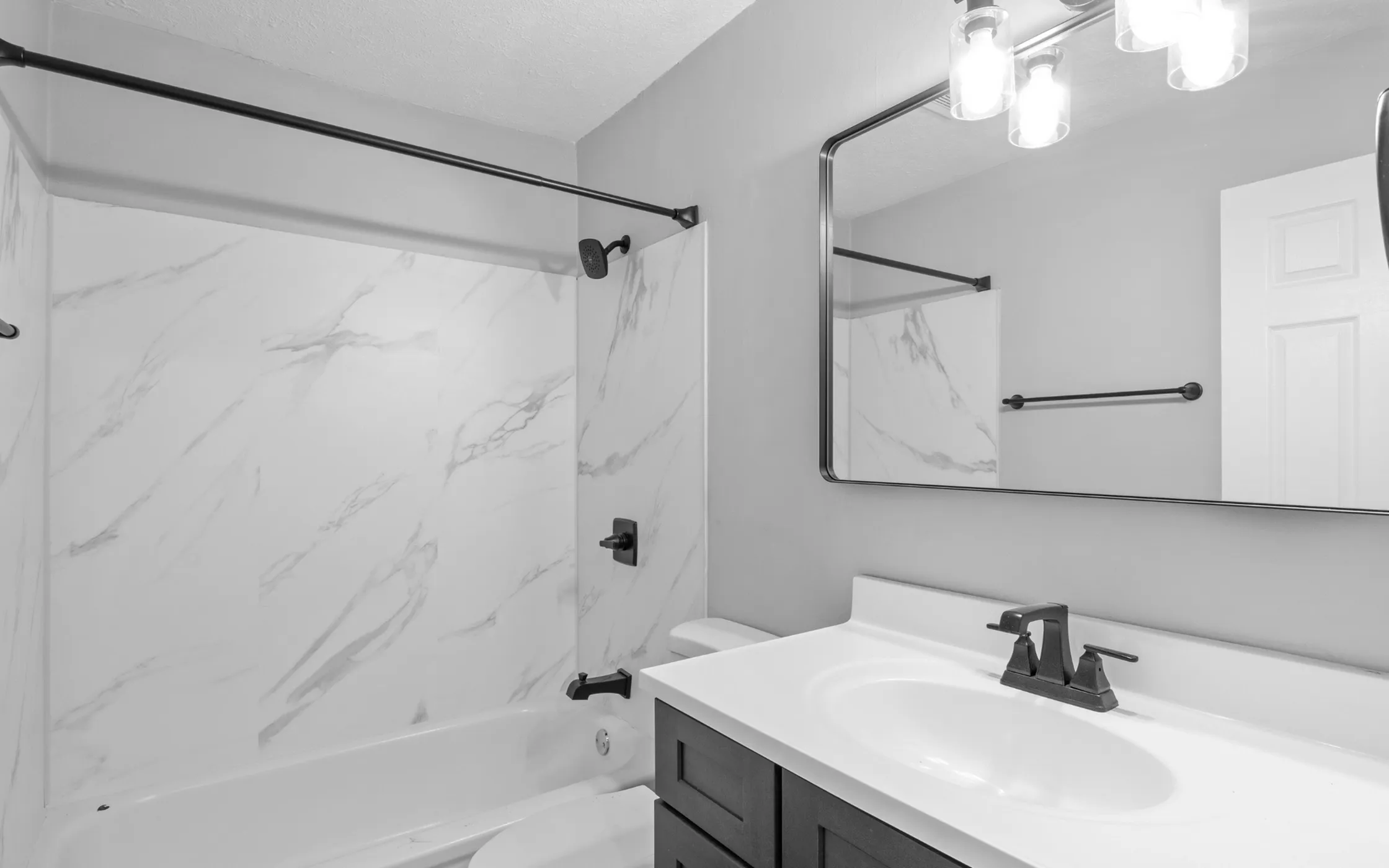 Modern bathroom with elegant marble shower walls, sleek fixtures, and a large mirrored vanity, alcove of turpin hills apartments