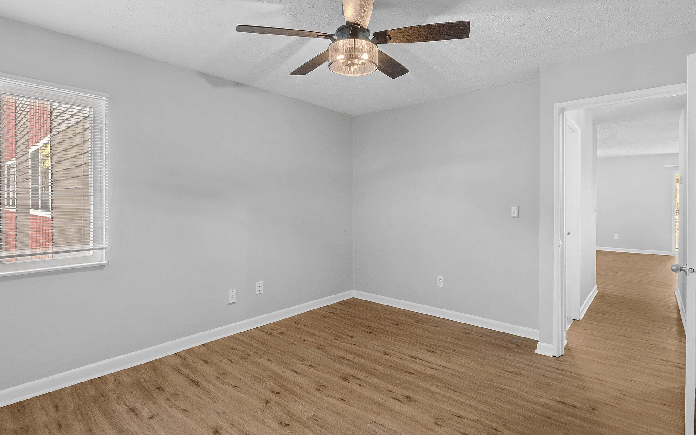 Bright empty room with elegant wood flooring, modern ceiling fan, and natural light through large window, Alcove of Turpin Hills Apartments