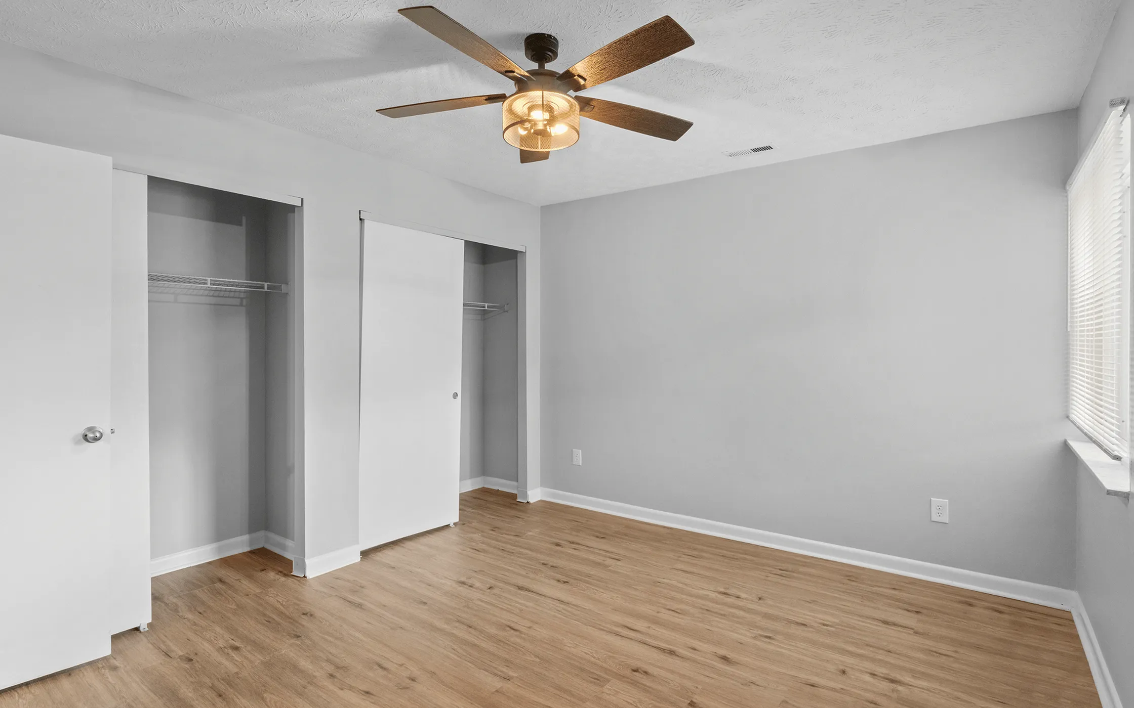 Bright and spacious bedroom featuring fresh paint, wood flooring, ceiling fan, and ample closet space.