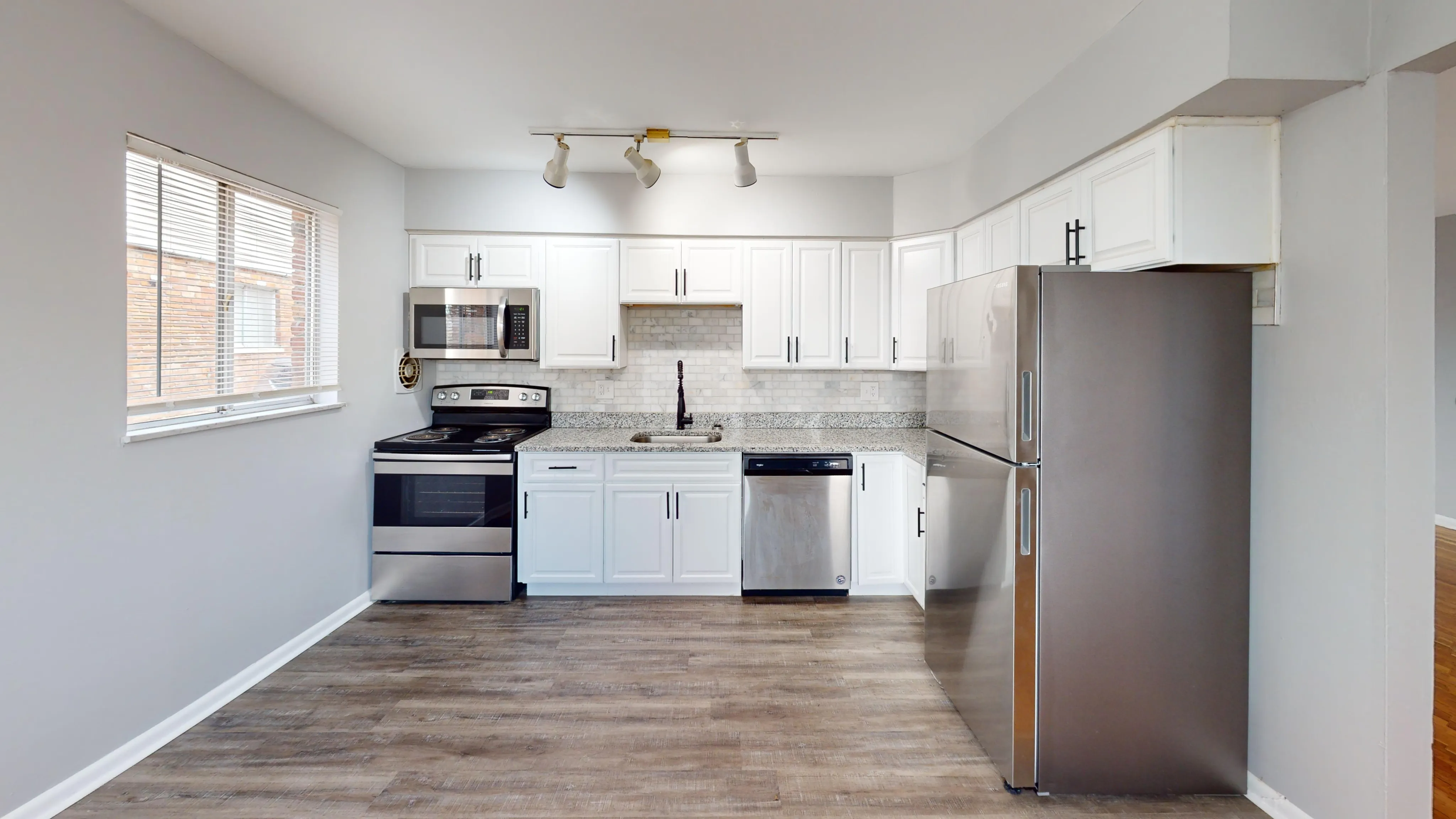 Modern kitchen with sleek stainless steel appliances, bright white cabinetry, and elegant granite countertops.
