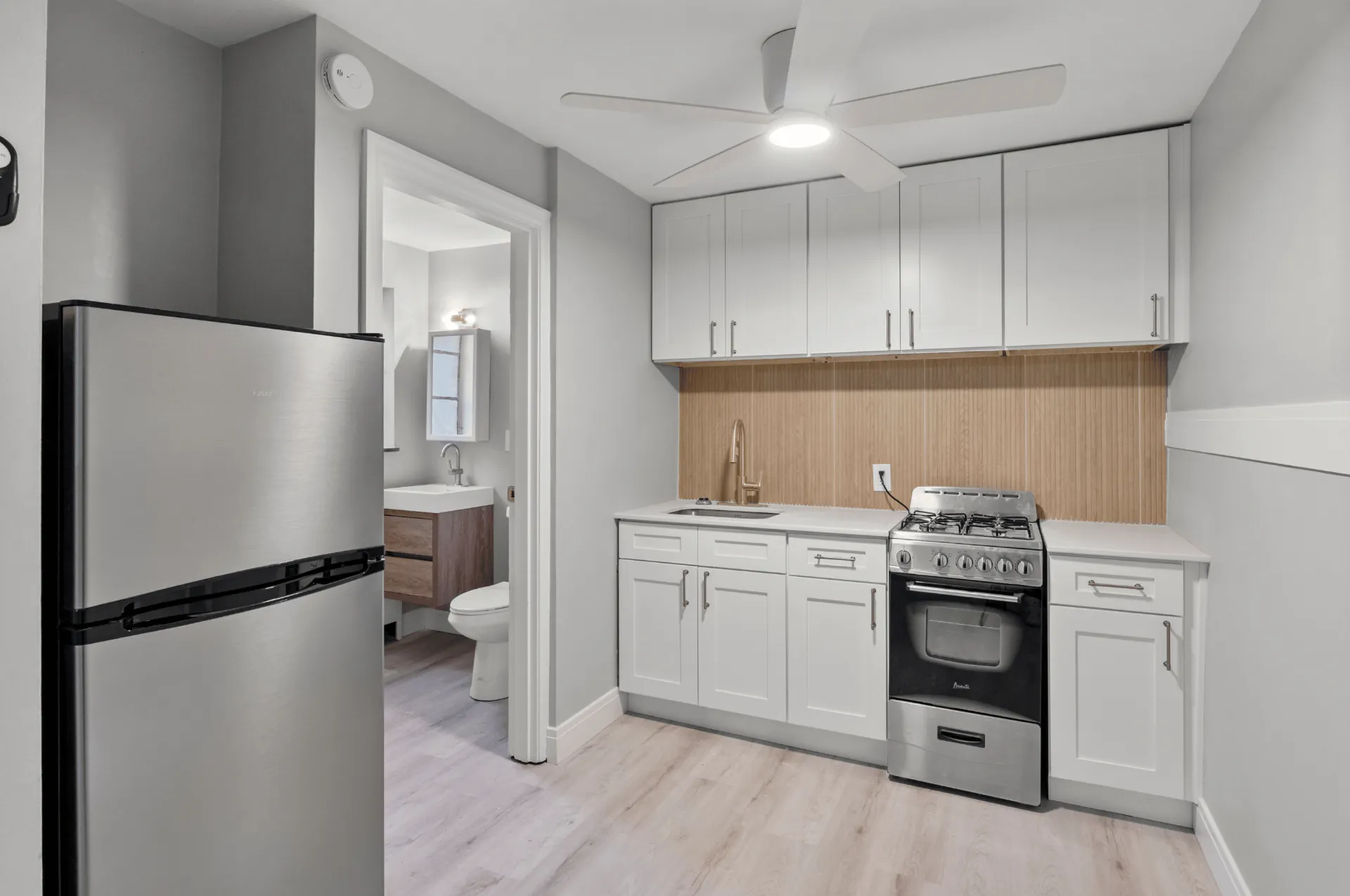 Modern kitchen with sleek stainless steel appliances, bright cabinetry, and open layout leading to a stylish bathroom.