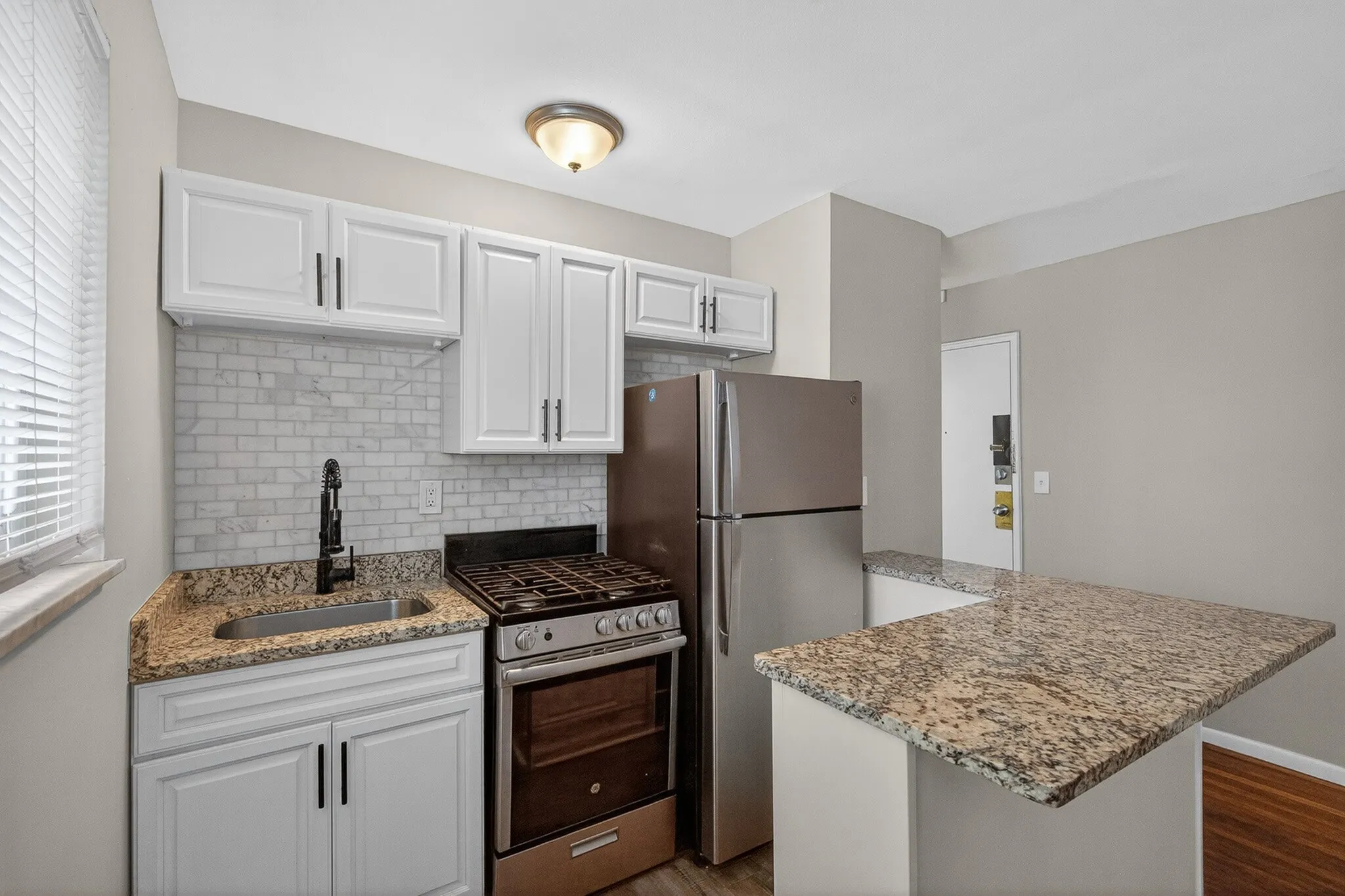 Modern kitchen with sleek granite countertops, stainless steel appliances, and elegant cabinetry, perfect for a stylish apartment.