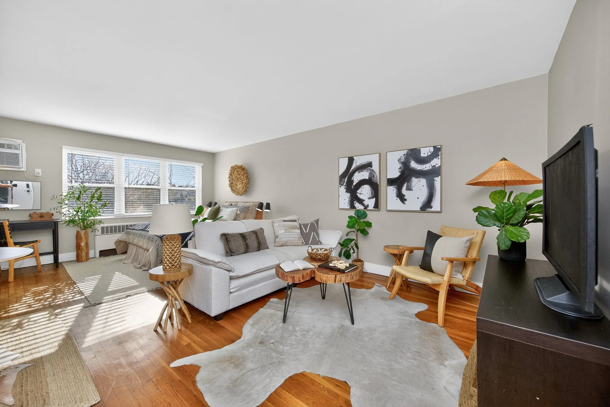 Inviting living room with abundant natural light, cozy seating, modern art, and stylish decor.