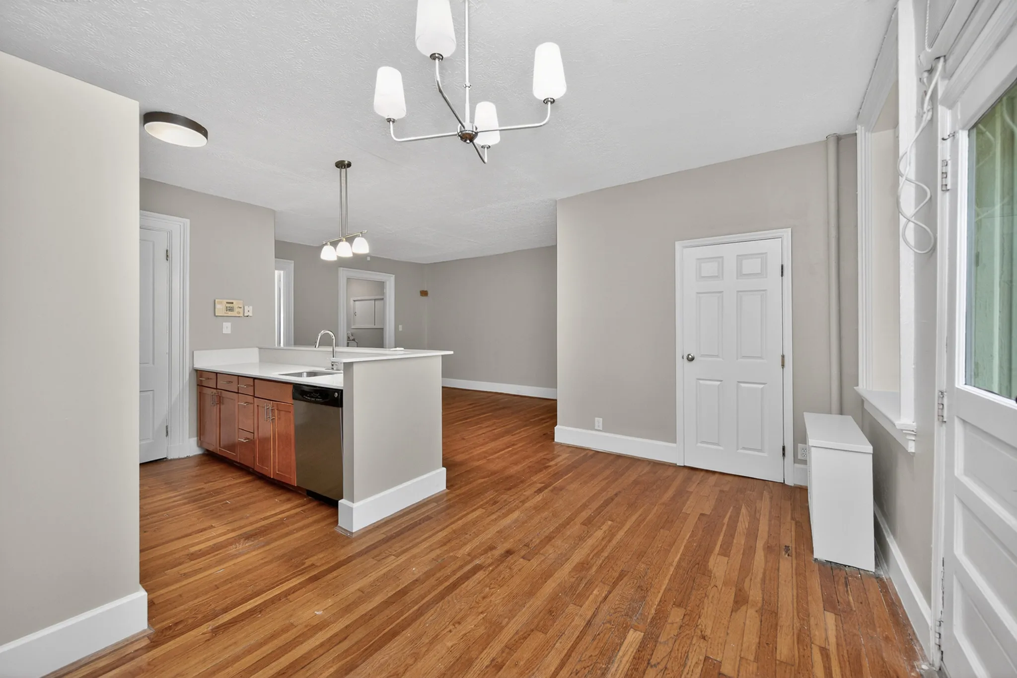 Modern open-concept living space with sleek hardwood floors, a stylish kitchen island, and elegant lighting fixtures.