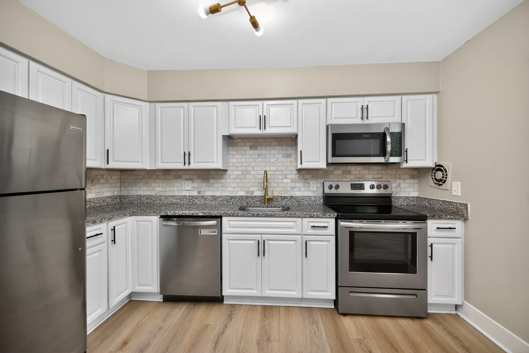 Modern kitchen with sleek design, featuring stainless steel appliances, white cabinetry, and granite countertops.