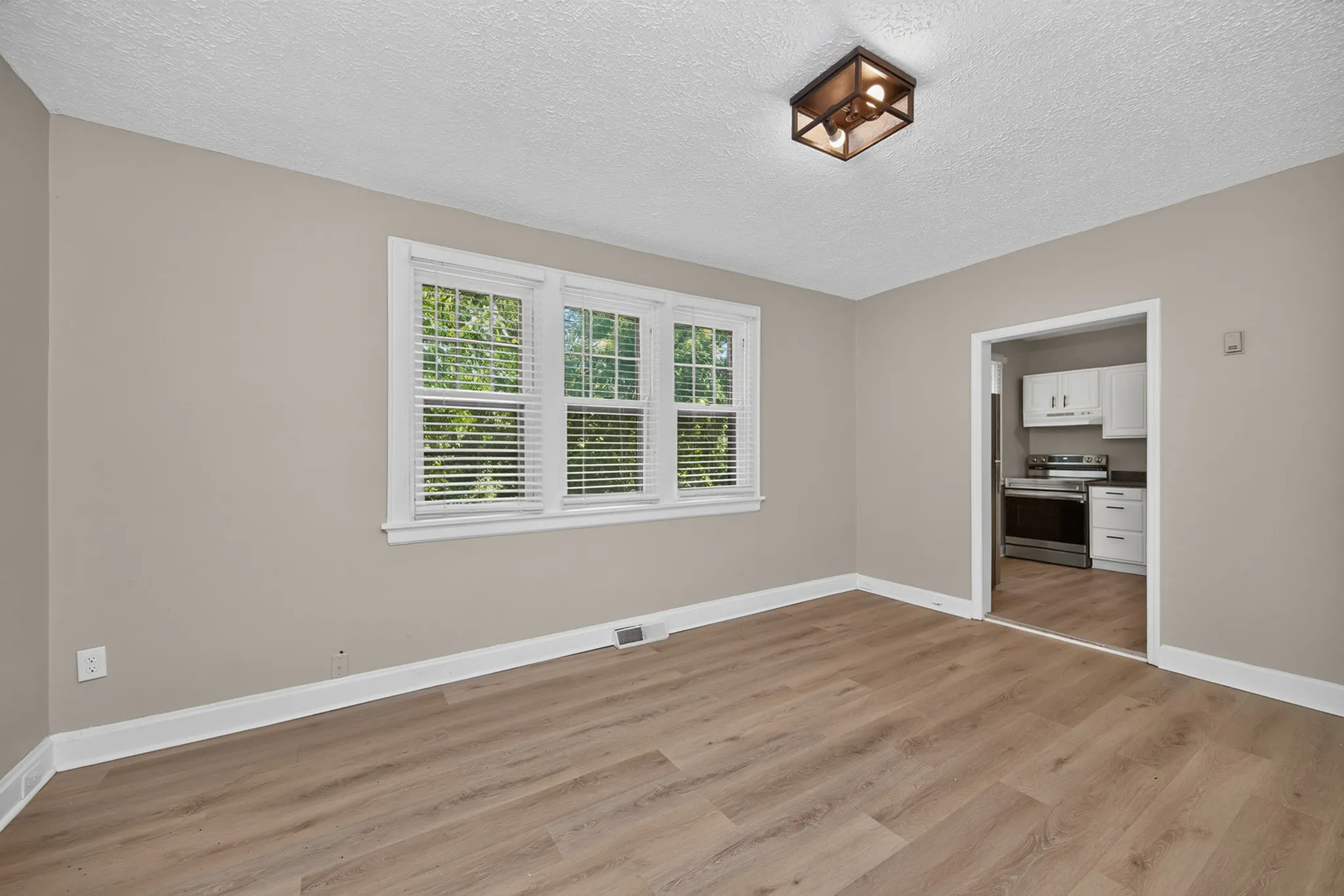 Bright, open living space with large windows and modern kitchen featuring stainless steel appliances.
