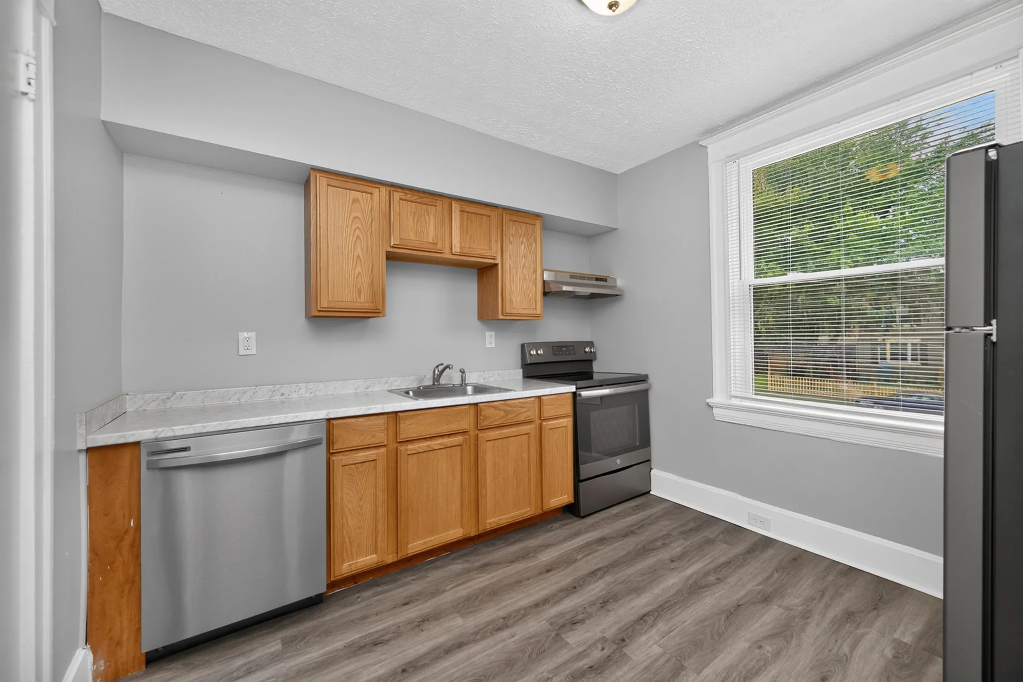 Modern kitchen with sleek stainless steel appliances, wood cabinetry, and large window for natural light.