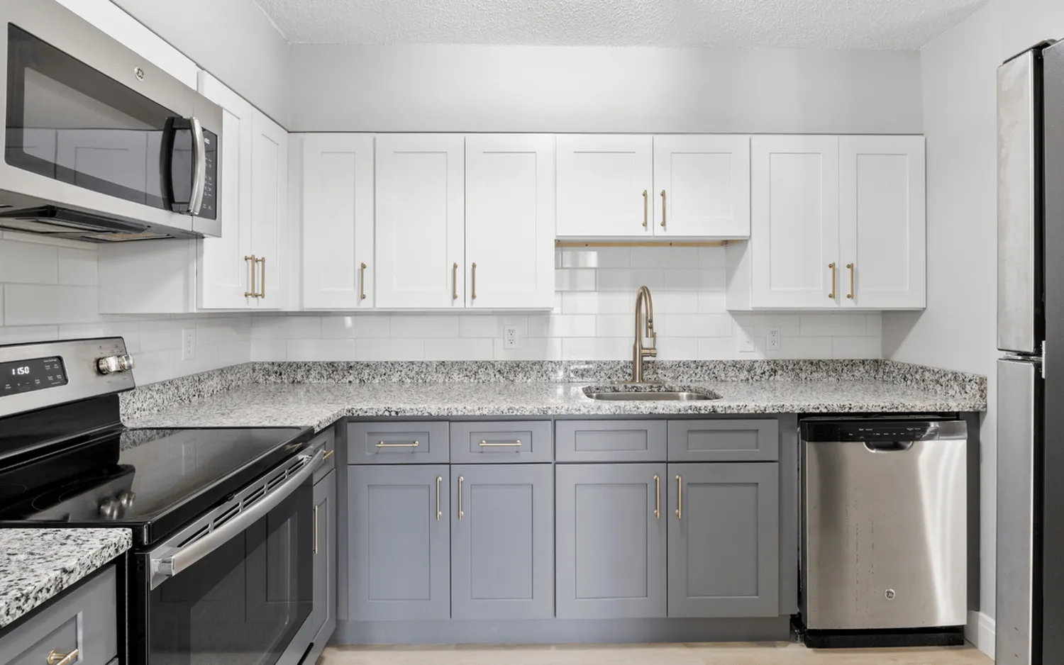 Modern kitchen with stylish granite countertops, stainless steel appliances, and elegant two-tone cabinetry.