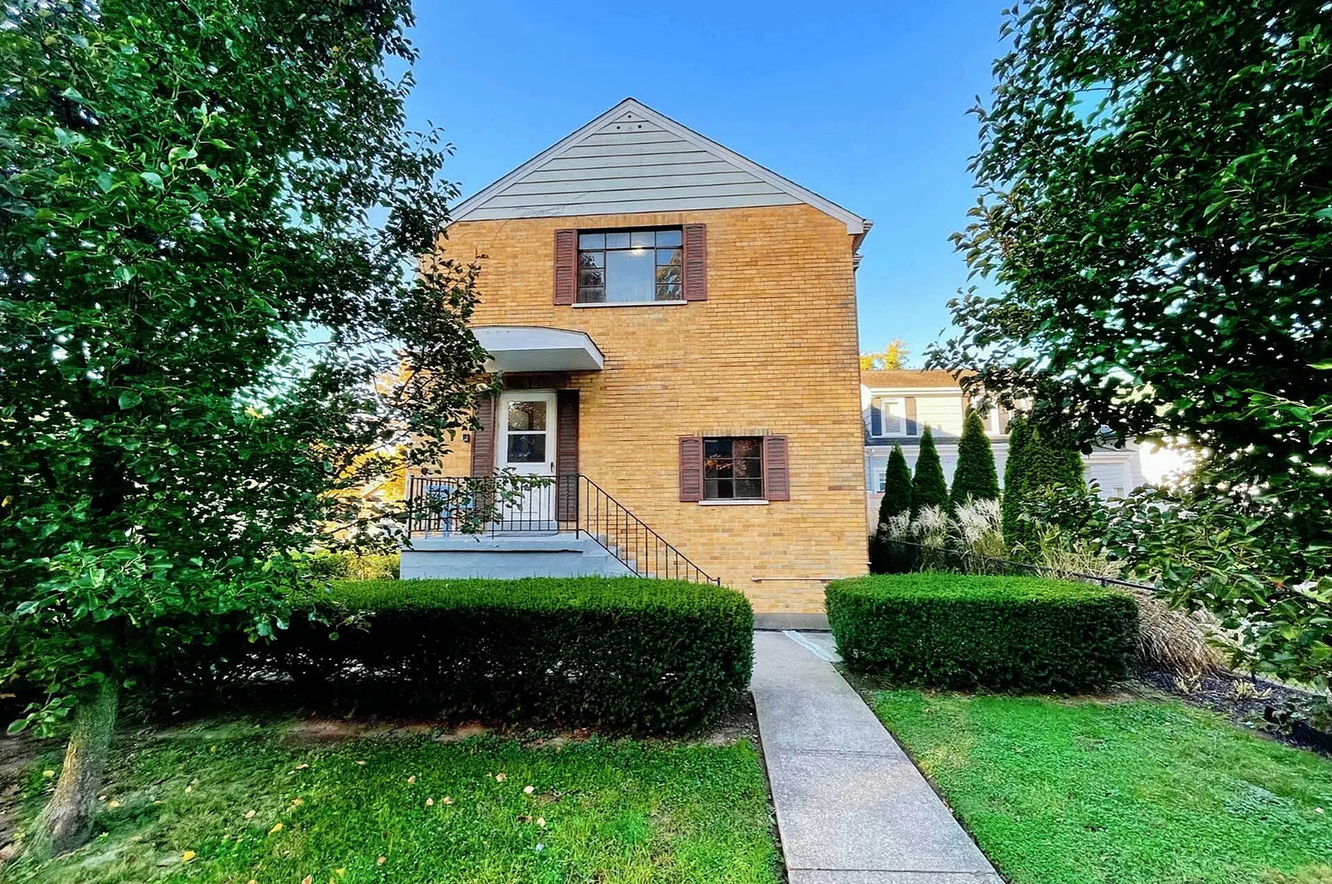 Charming living with a quaint front porch and lush green garden, ideal for cozy living.