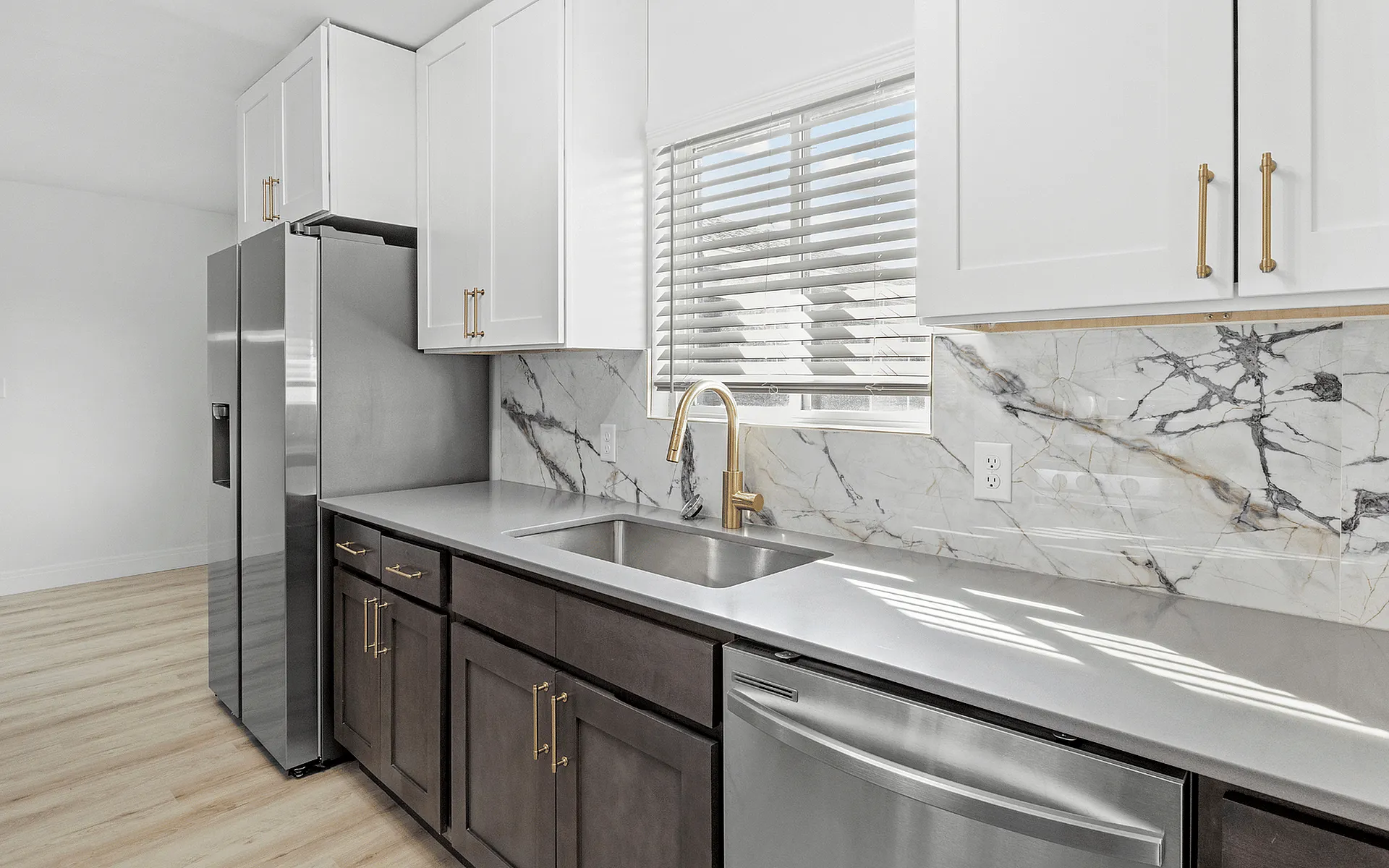 Modern kitchen with sleek stainless steel appliances, quartz countertops, and elegant marble backsplash, featuring bright natural lighting. The Cadence of Newport, Apartments in Newport, KY.