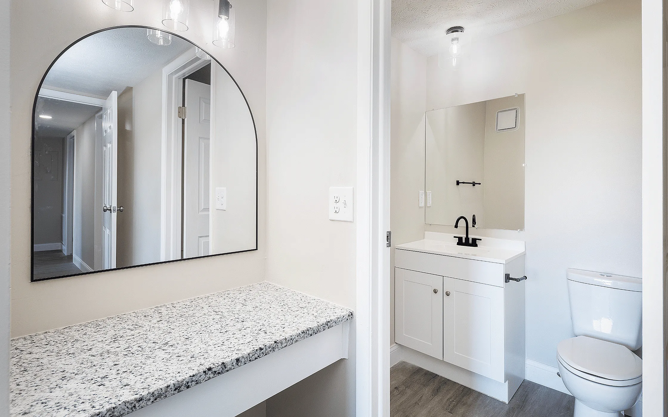 Bright and modern bathroom with elegant granite countertop, stylish mirror, and sleek white fixtures.