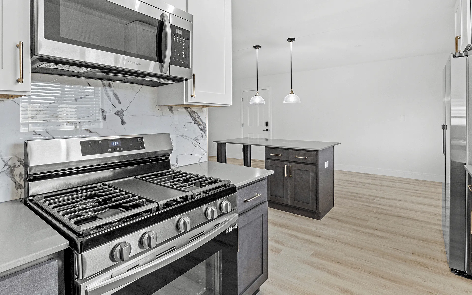 Elegant kitchen design with modern stainless steel appliances, luxurious marble backsplash, and chic pendant lighting over a central island.