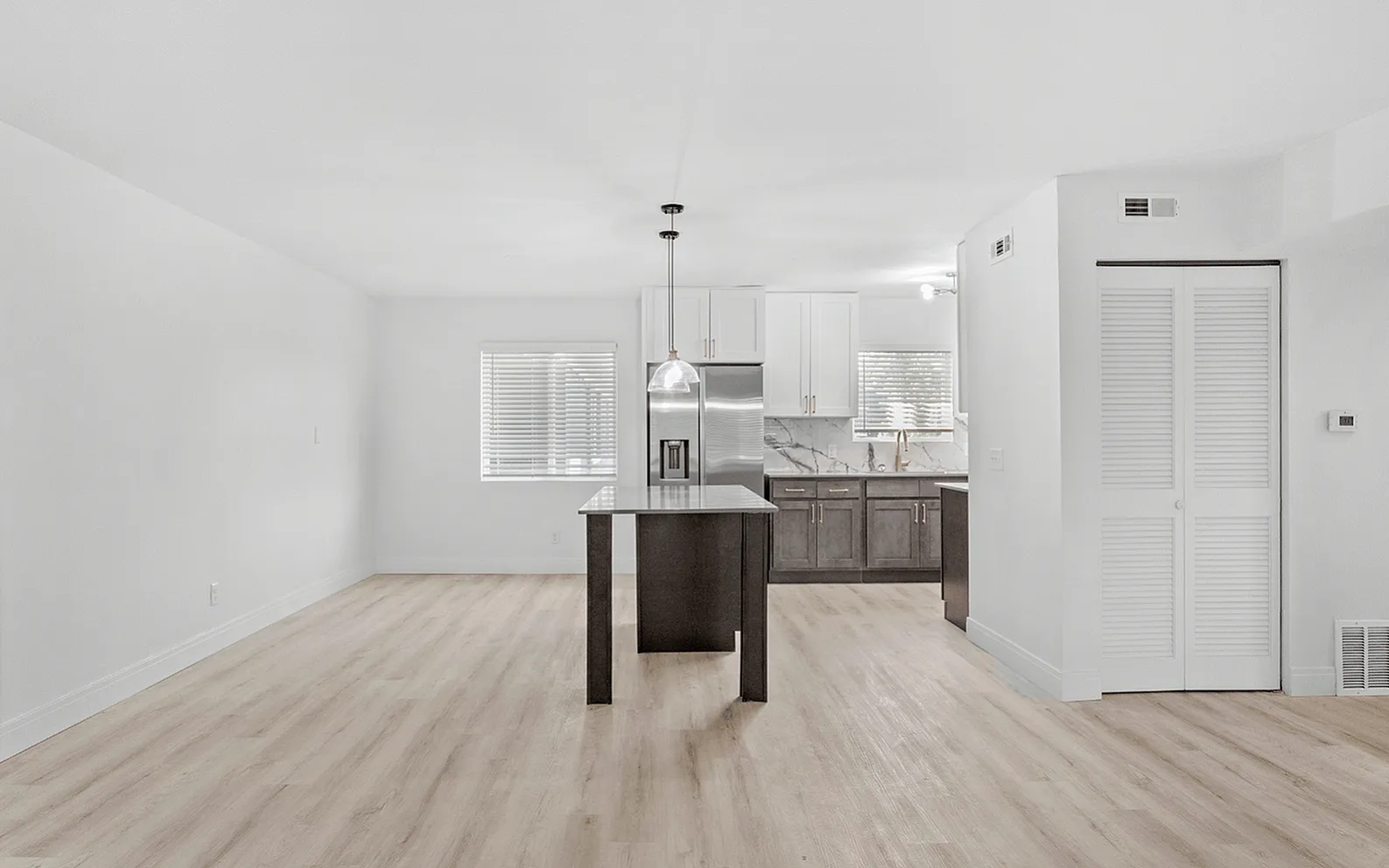 Contemporary Overhead Lighting, Bright and modern open-plan apartment kitchen and living area with sleek cabinetry, large island, and stylish light fixtures.