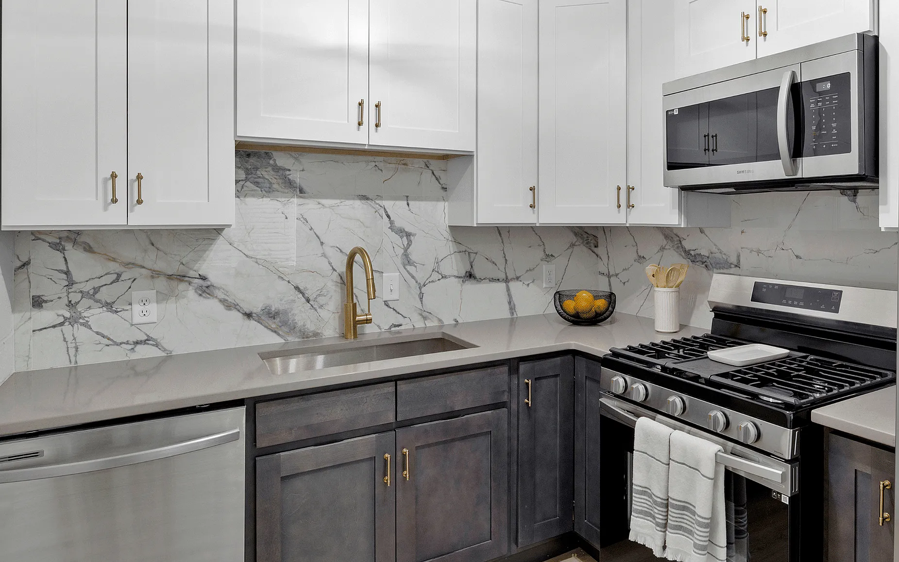 Modern kitchen with sleek stainless steel appliances, elegant marble backsplash, and stylish cabinetry.