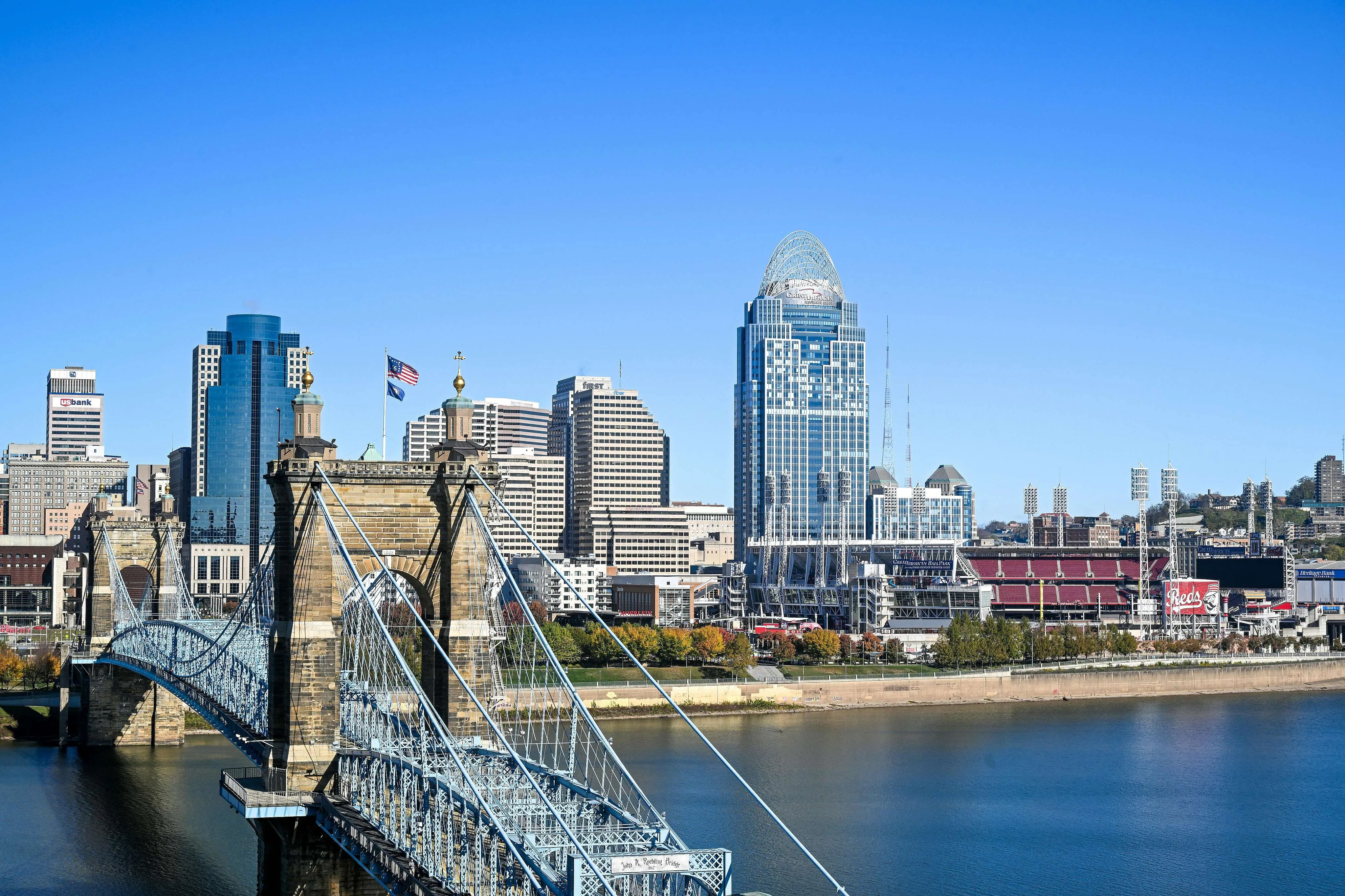 Stunning cityscape view featuring a historic bridge over a calm river, framed by a vibrant skyline with modern skyscrapers and a bright blue sky.