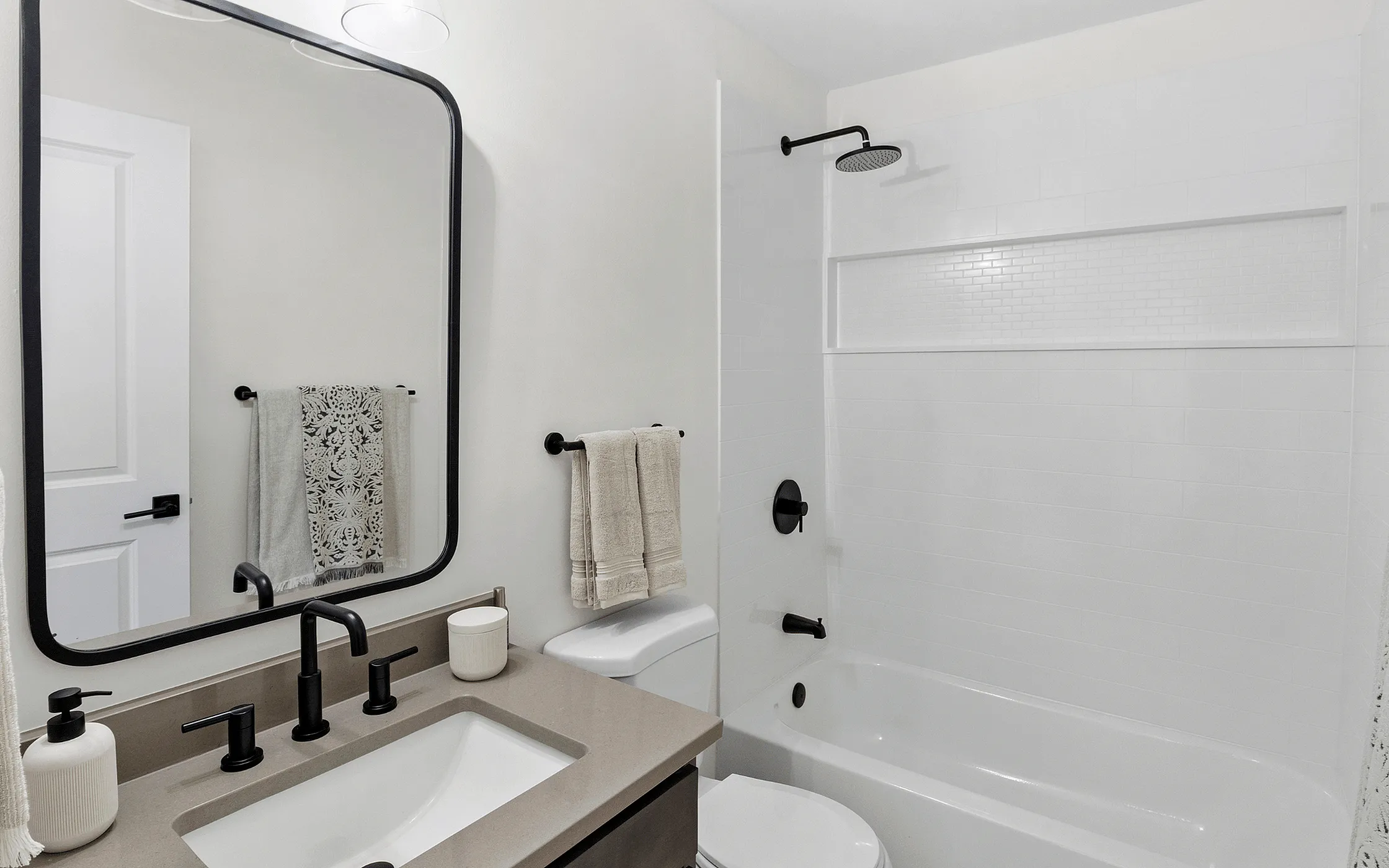 Chic modern bathroom featuring elegant black fixtures, a sleek vanity, and crisp white tiles for a fresh, contemporary feel.