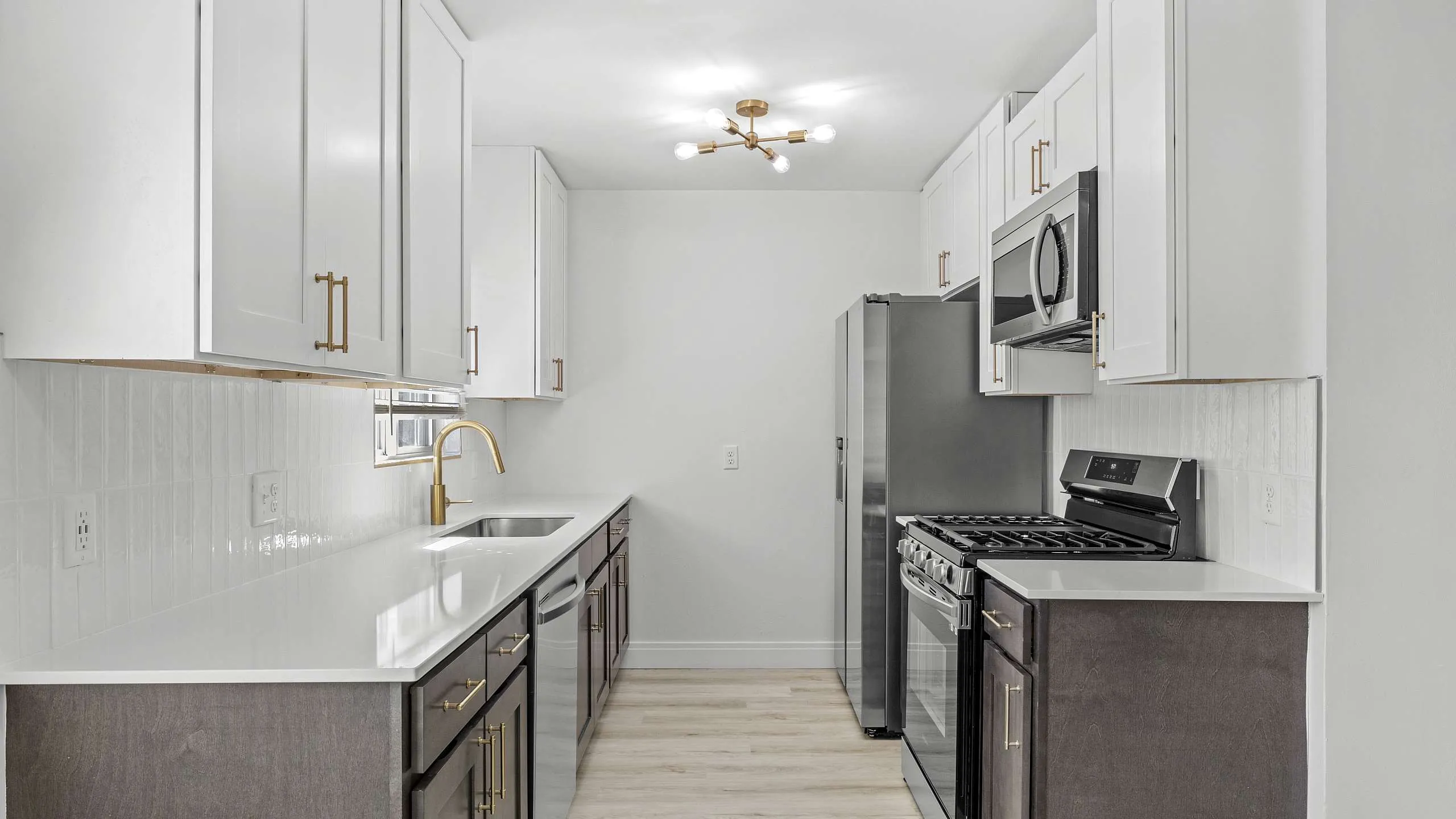 Modern kitchen with sleek white cabinetry, gold fixtures, and stainless steel appliances for a luxurious touch.